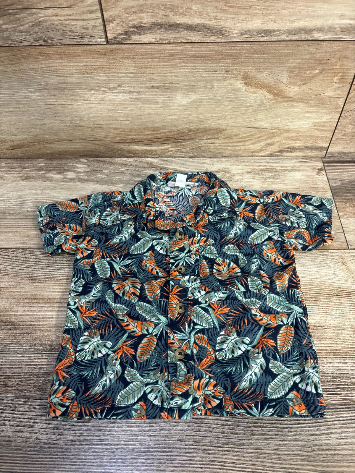 Front view of Mick Mack green floral button-up shirt showcasing button-front design with a wood-look background