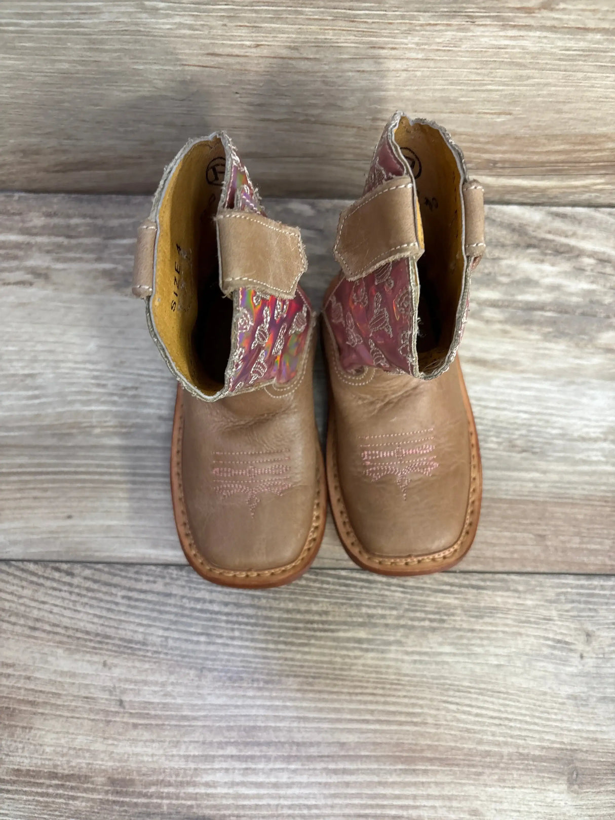 Top view of Roper Kids Looking Glass cowgirl boots size 4c in tan leather with pink floral lining and pink embroidery on wood plank floor