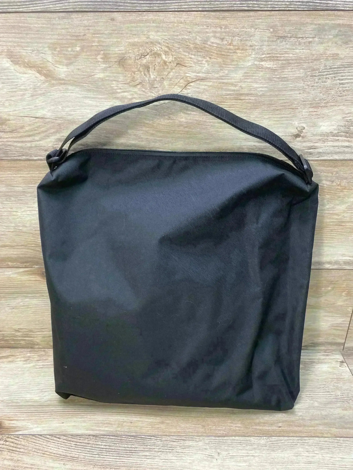 Front view of Matriarch pregnancy support maternity belt in black zippered storage pouch with handle on wood background