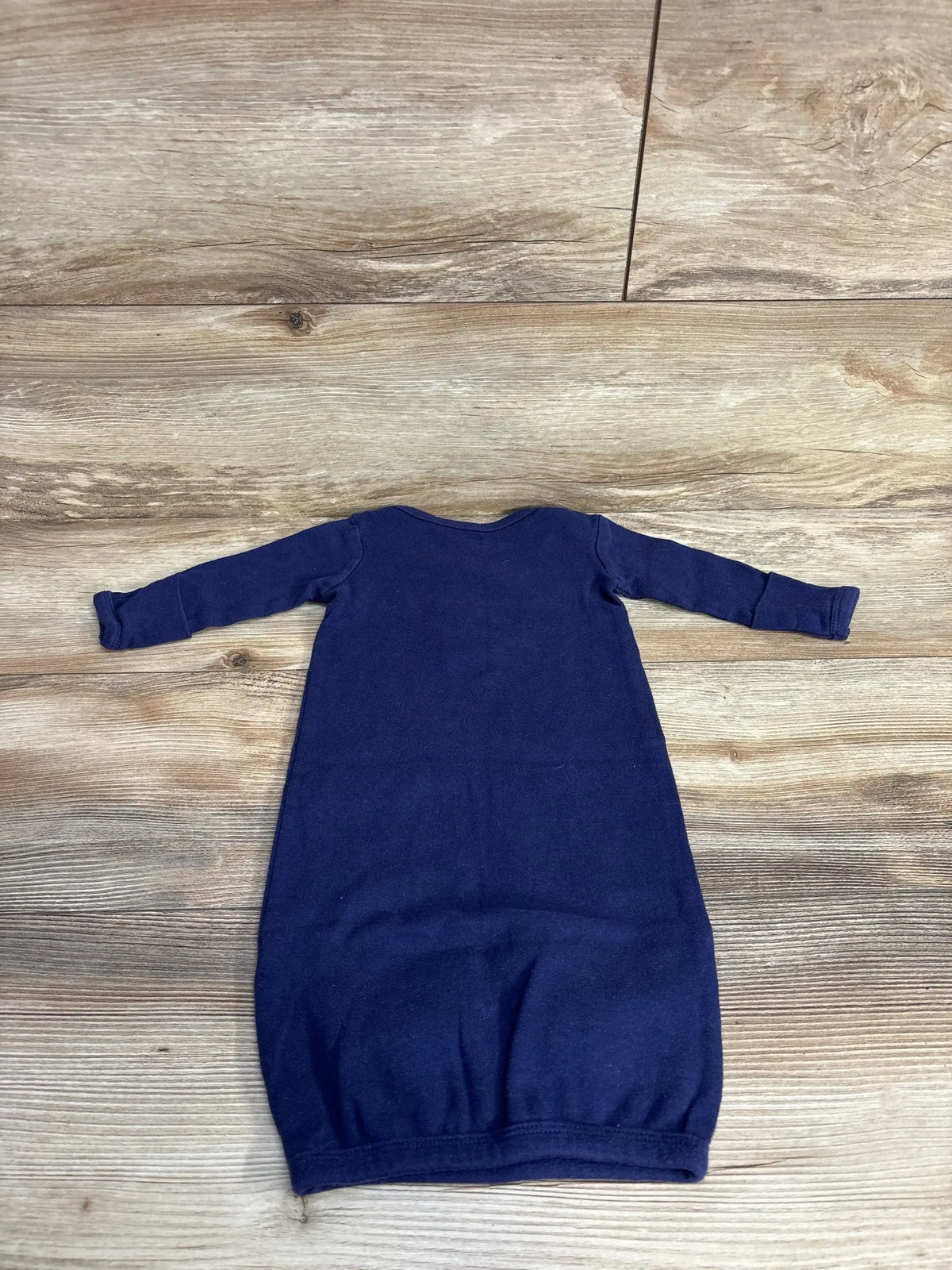 Navy blue long-sleeve infant gown laid flat on wood floor