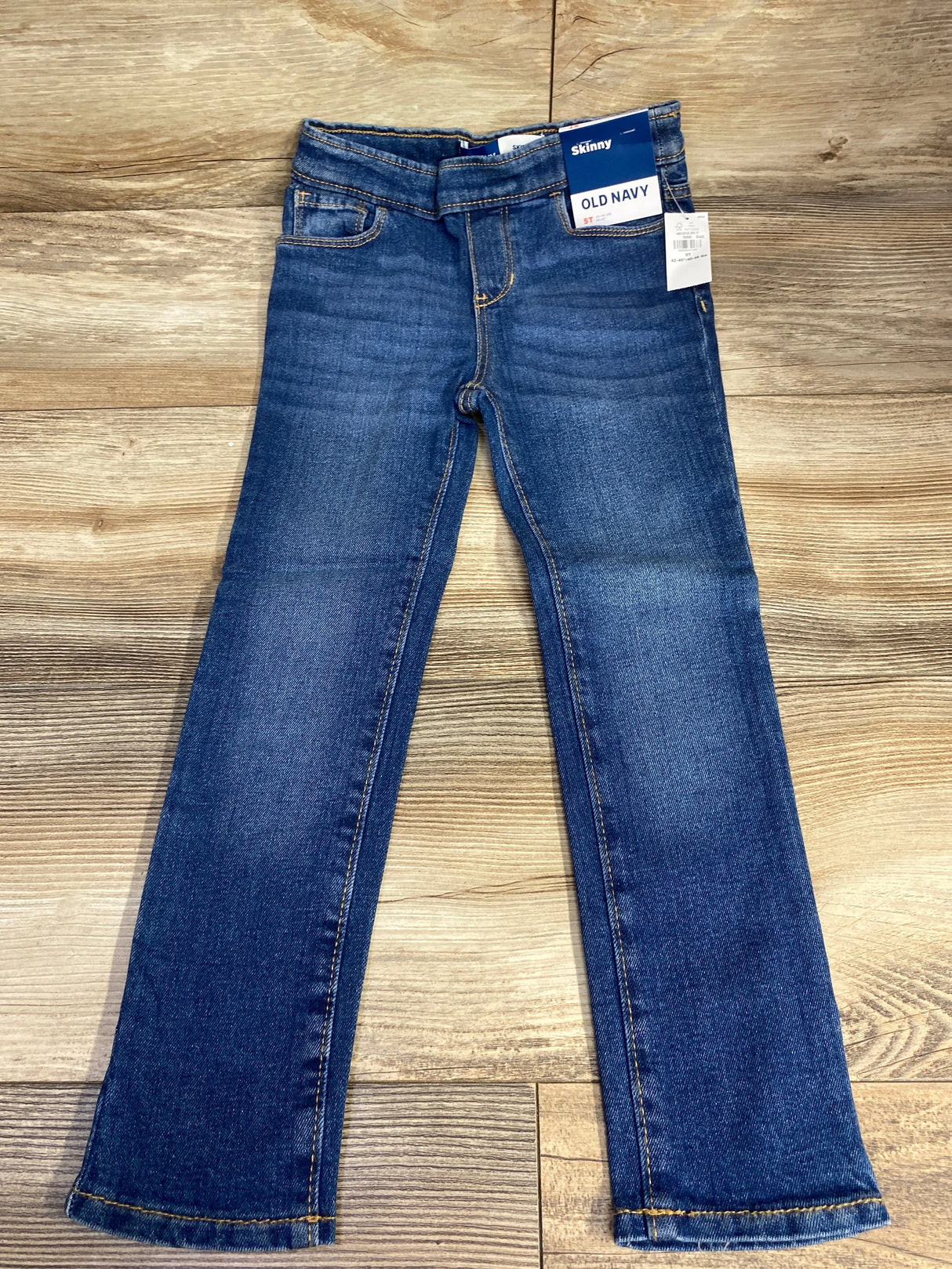 Old Navy kids blue skinny jeans with tags on wooden floor, gently used children's clothing