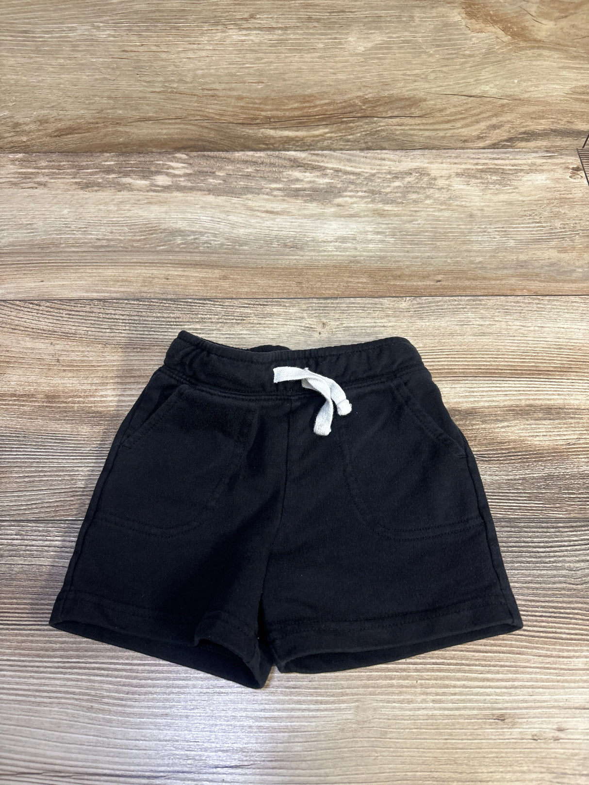 Flat lay of Cat & Jack knit toddler shorts showing elastic waistband with white drawstring and front pockets on wood background