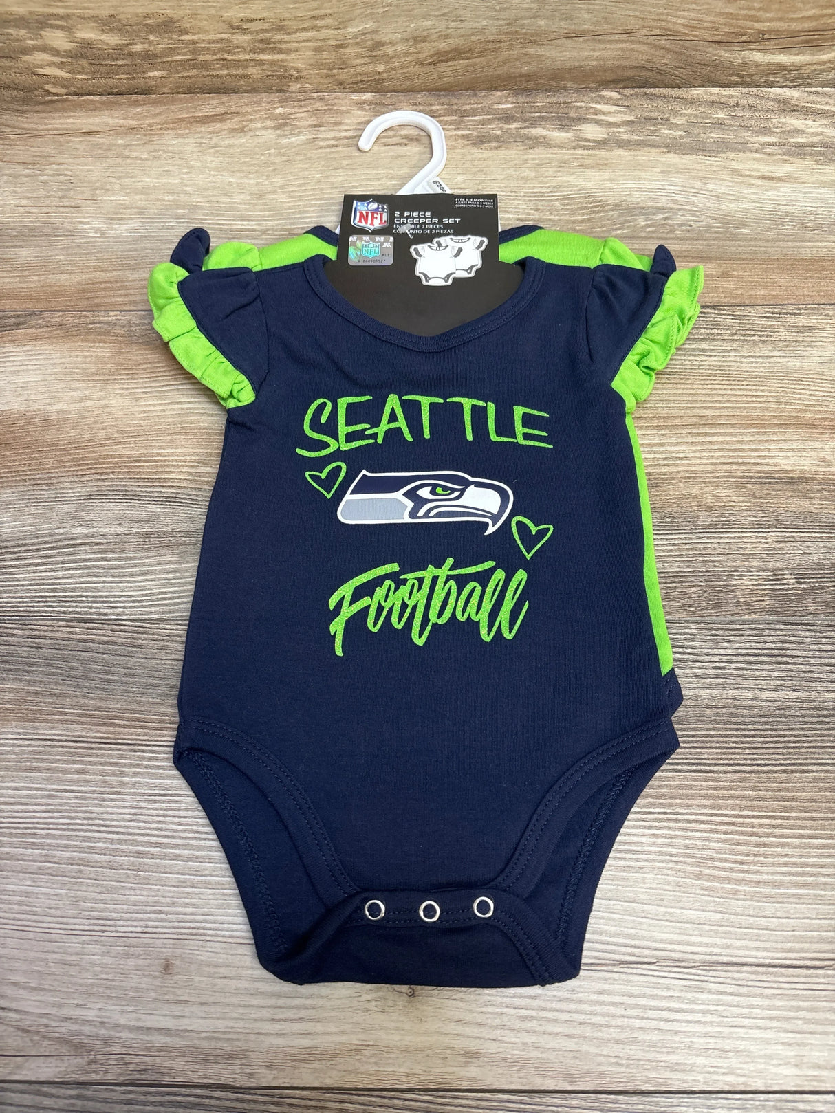 Navy and green 2-piece Seattle Seahawks baby creeper set with logo and ruffled sleeves on wooden background