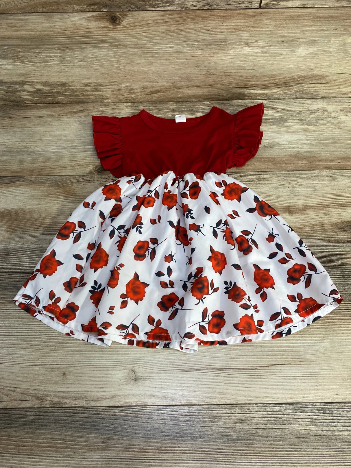 Flat-lay of red Shein toddler ruffle-sleeve dress with white rose-print skirt, size 12–18 months, on wood background