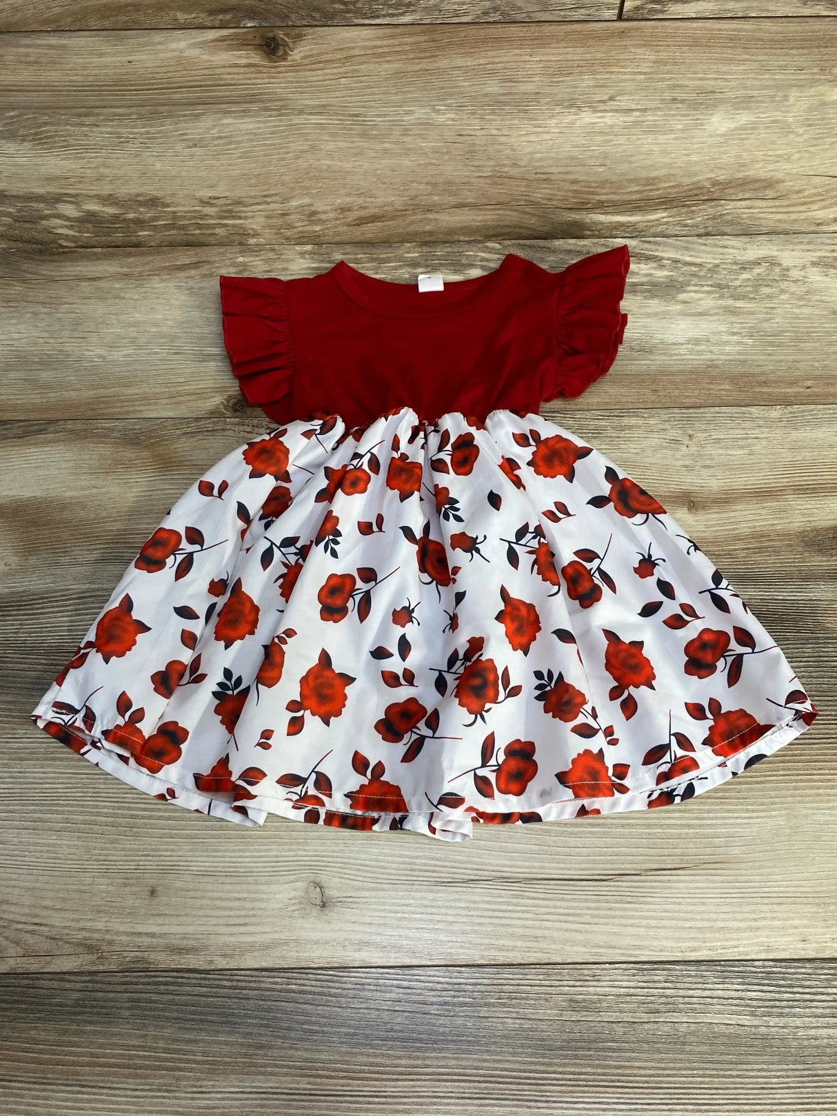 Flat-lay of red Shein toddler ruffle-sleeve dress with white rose-print skirt, size 12–18 months, on wood background