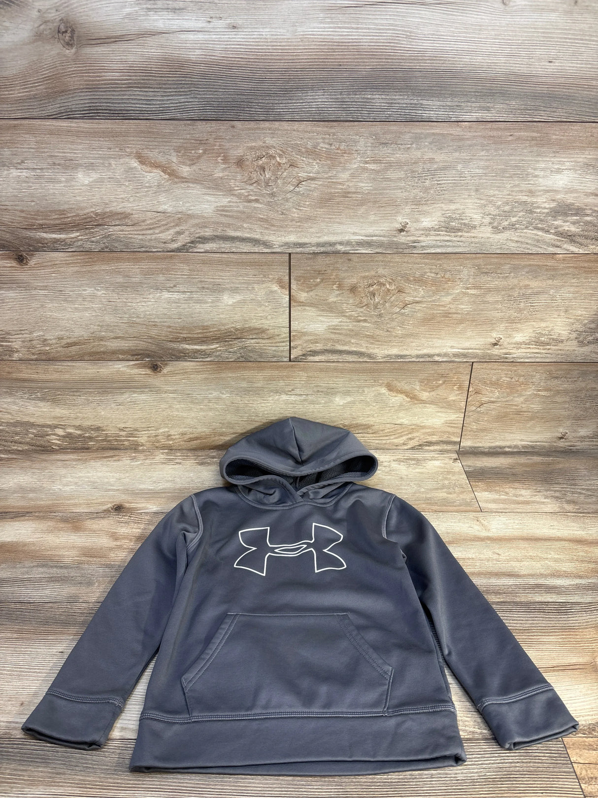 Gray Under Armour kids hoodie with white logo, laid on wooden floor