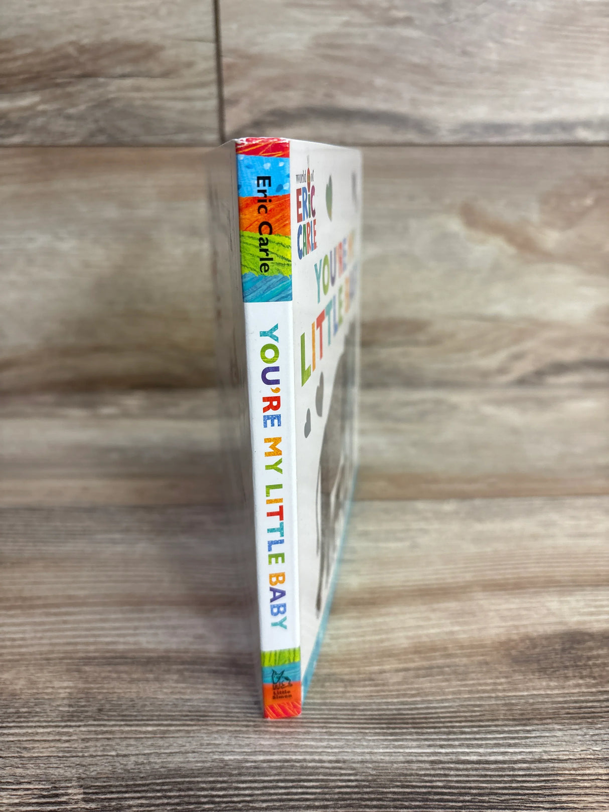 Spine of the Eric Carle children's book "You're My Little Baby" with colorful text and wooden background