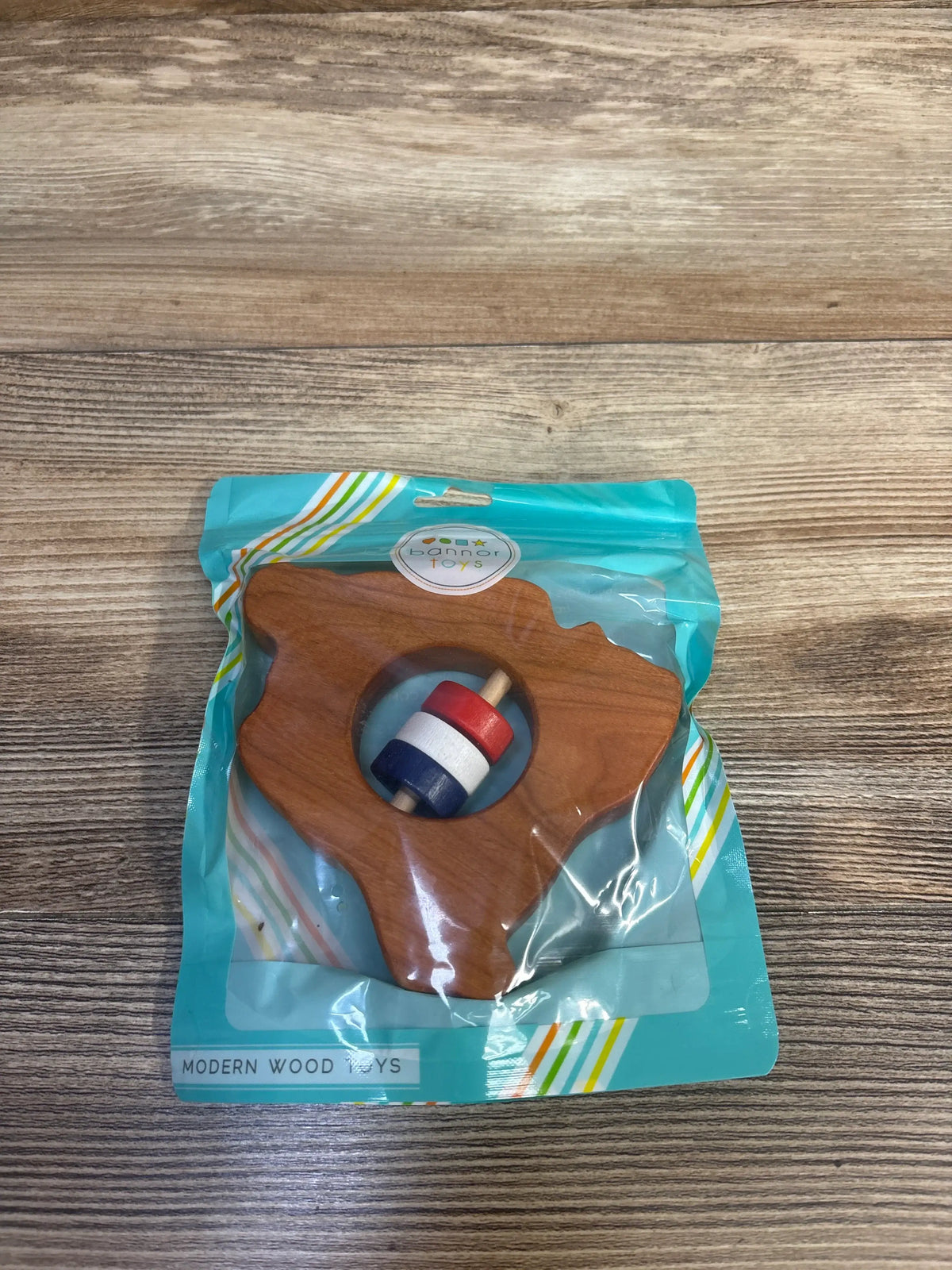 Front view of NEW Bannor Toys Wooden Rattle showcasing its light Maple wood tree shape and multicolored beads in clear packaging
