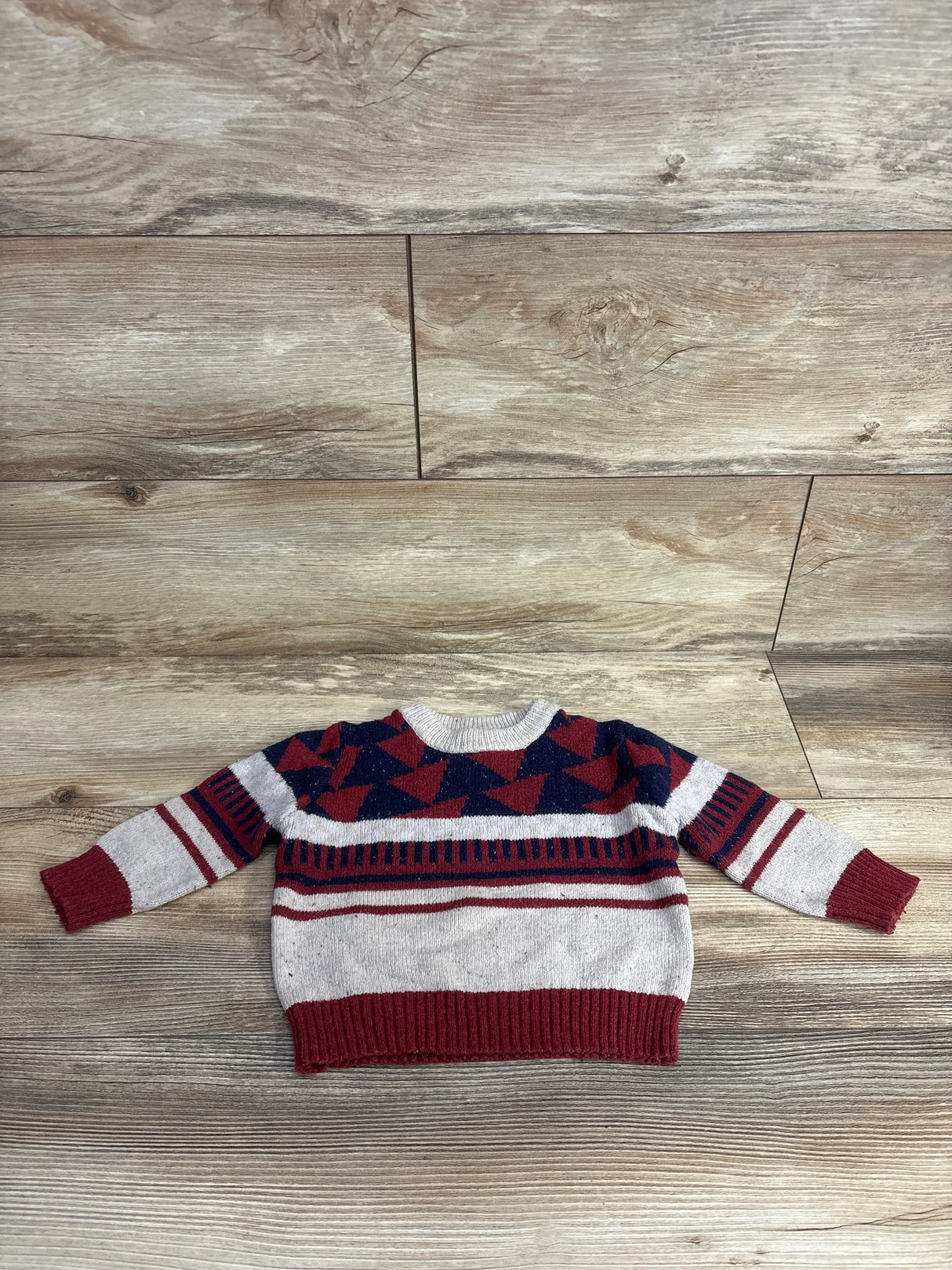 Red and navy geometric pattern toddler sweater on wood background, kids resale clothing