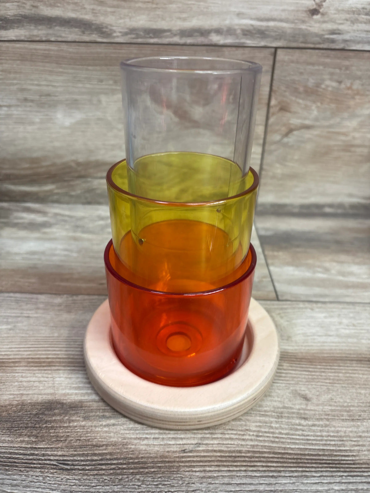 Front view of Lovevery Transparent Tube Tower 4pc showcasing four stacked transparent colored tubes on a wooden base