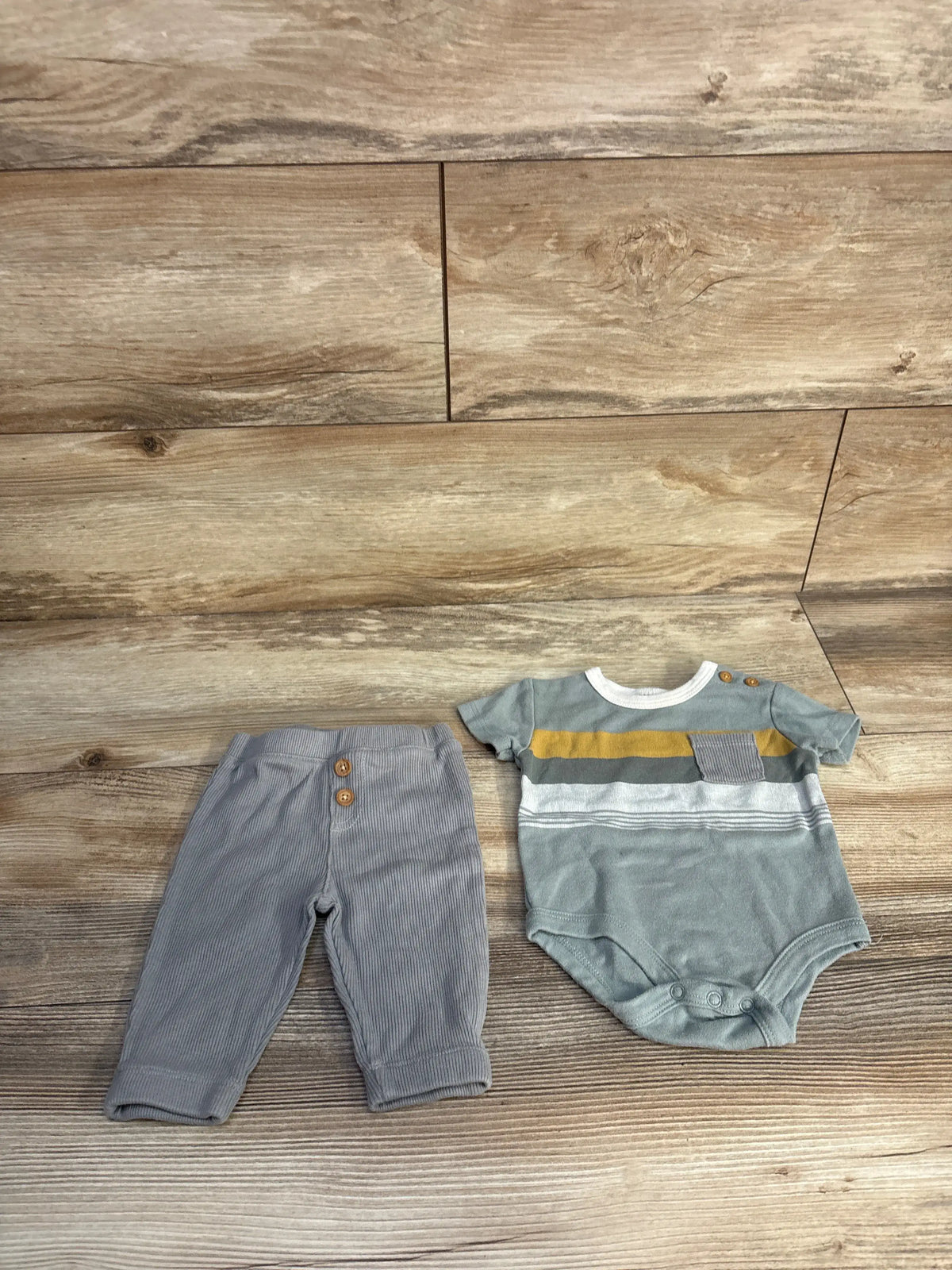 Top-down view of Mario Lopez green bodysuit and pants set showcasing striped bodysuit and coordinating pants on wood flooring