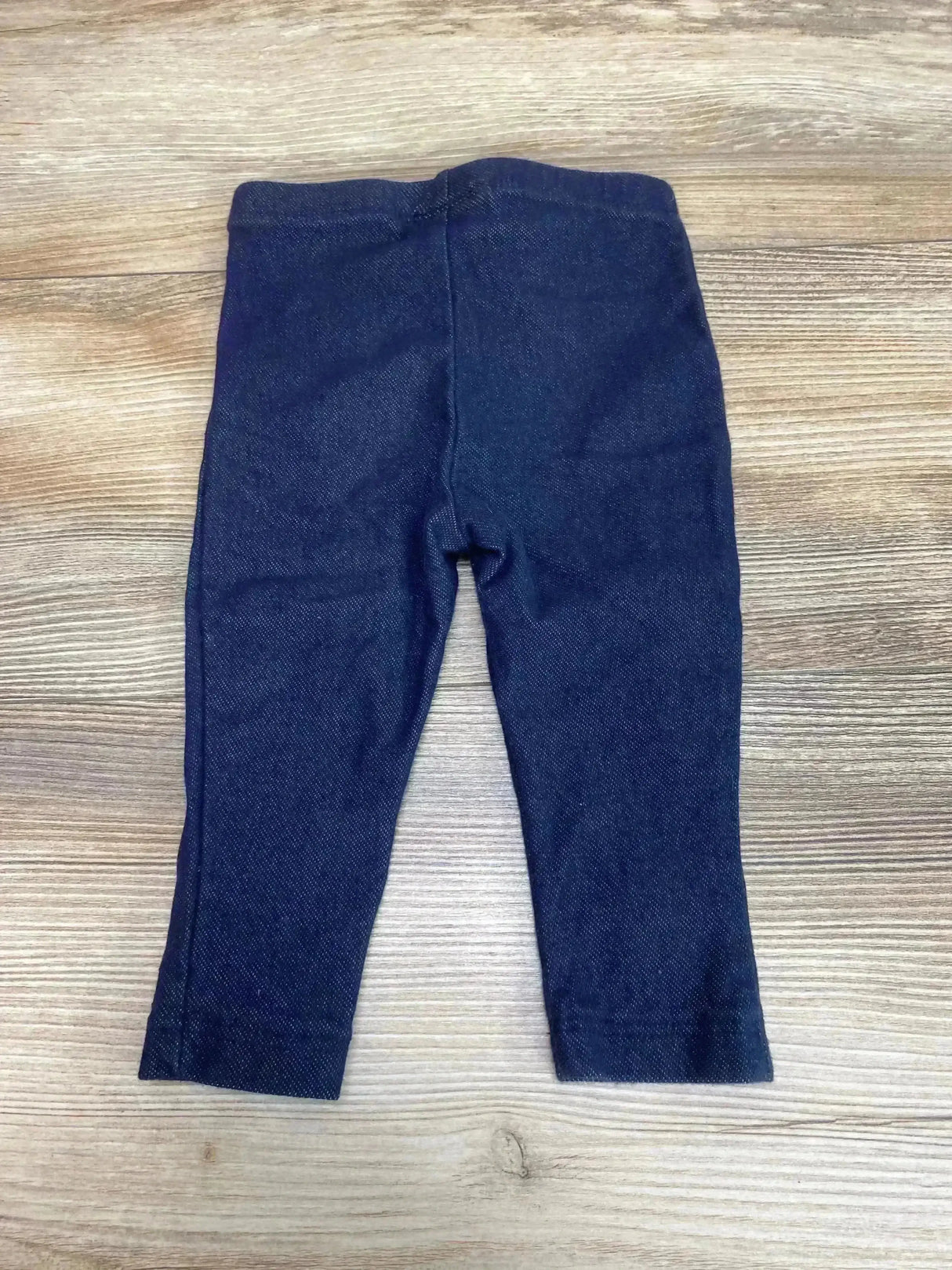 Flat lay of Calvin Klein toddler leggings size 12M in dark blue showing elastic waist on light wood surface