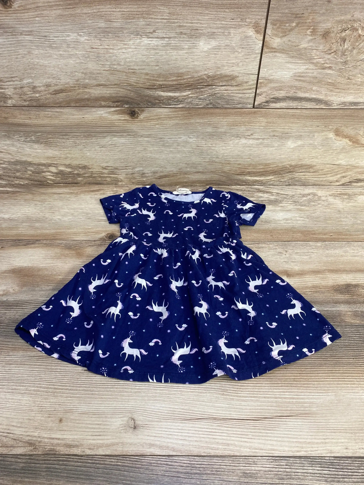 Flat lay of Emma and Elsa blue size 2T toddler dress showing unicorn print, short sleeves, and gathered skirt on light wood floor