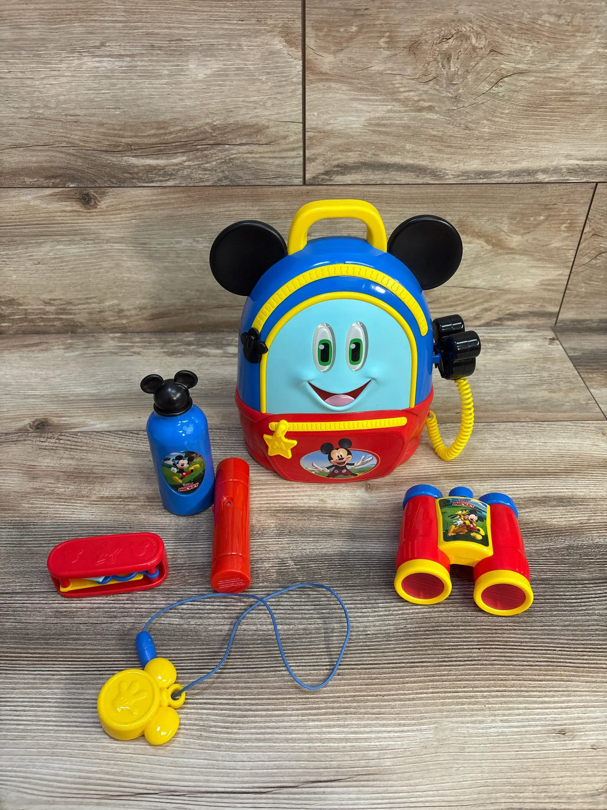 Front view of Mickey Mouse Funhouse Adventures Backpack Playset showing the backpack and pretend accessories on a wood floor