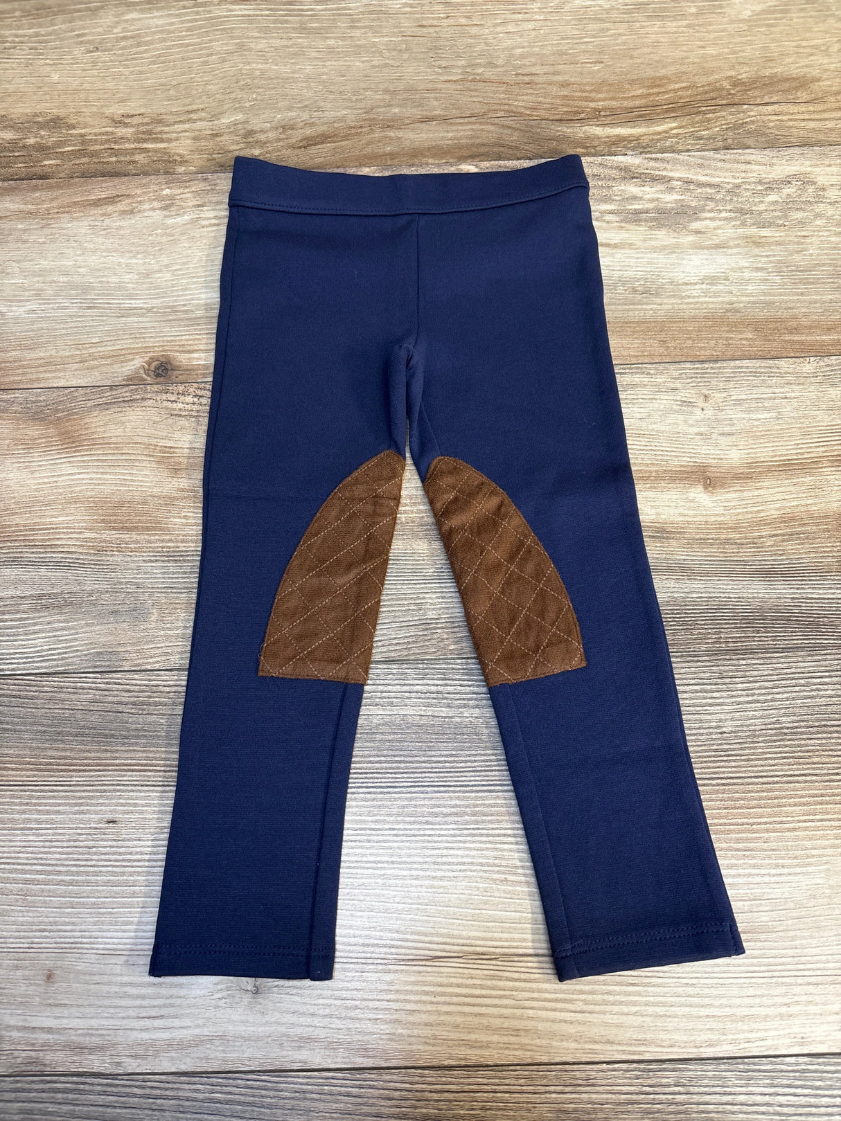 Navy blue toddler leggings with brown quilted knee patches on wood background