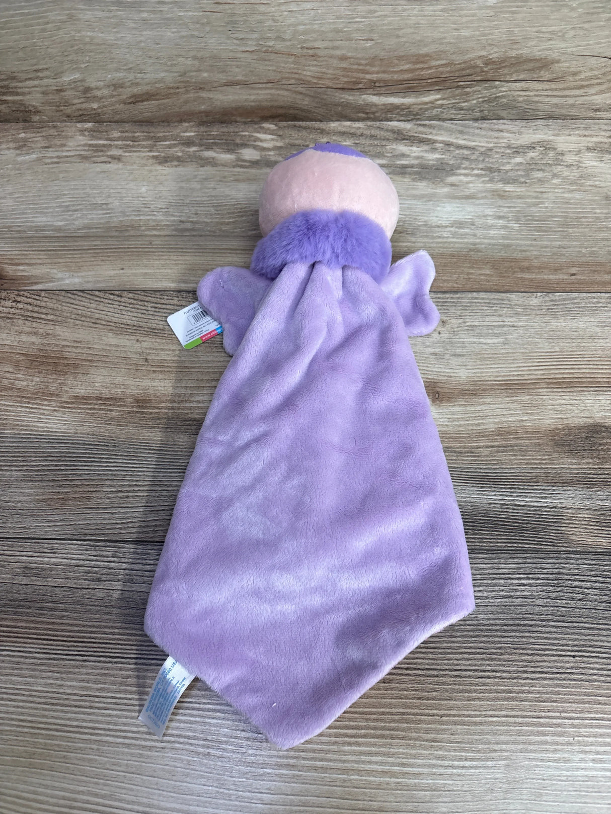 Plush lavender baby security blanket with soft doll head, on wood background
