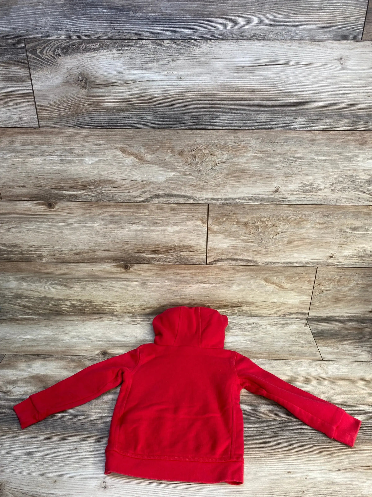 Red children's hoodie laid flat on wood background, back view, gently used kids clothing