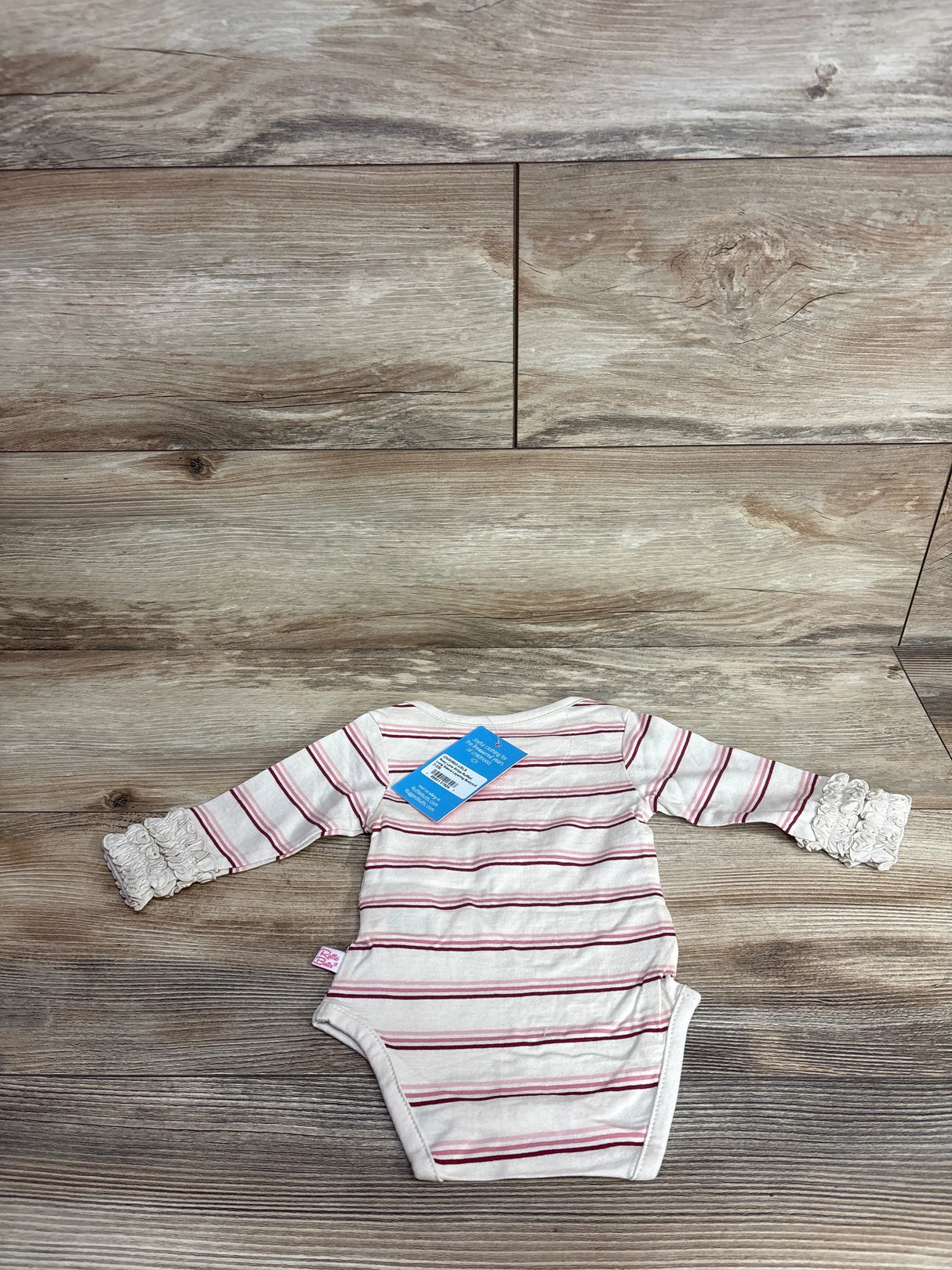 Striped long sleeve baby bodysuit with lace cuffs on wood background