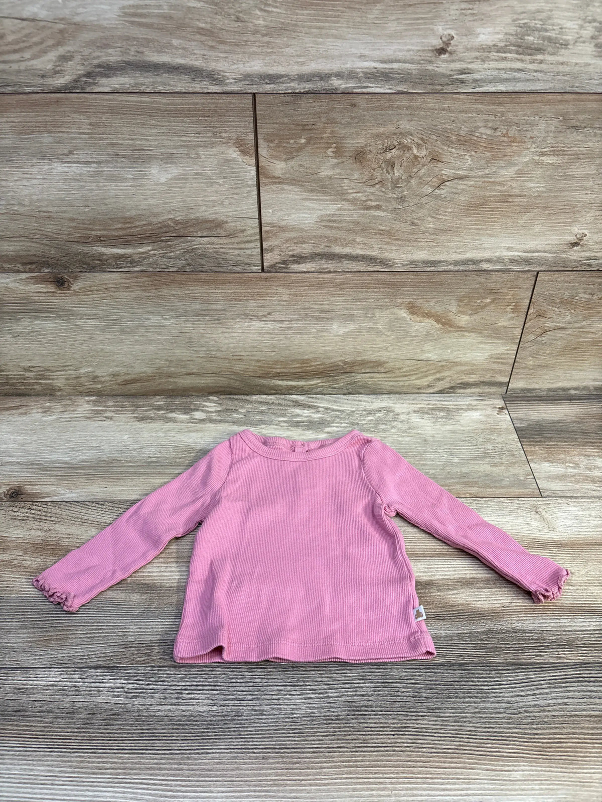 Baby Gap ribbed long sleeve shirt in pink, size 6-12m, on a wooden background