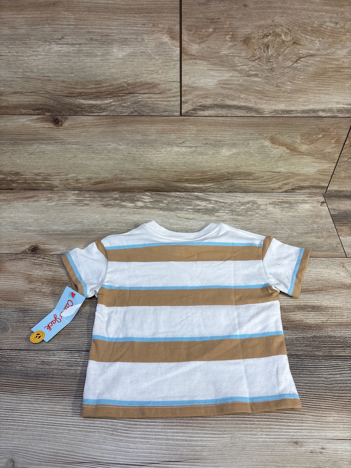 Back view of Cat & Jack toddler short-sleeve shirt showing white fabric with tan and light blue horizontal stripes and attached tag on wood background