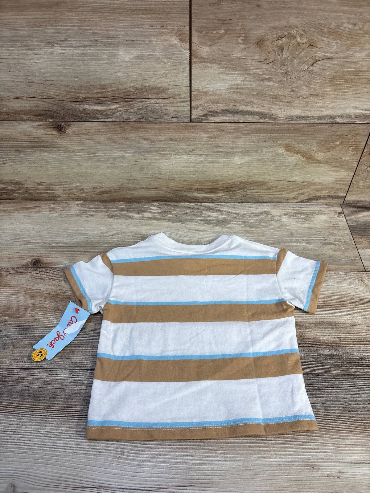 Back view of Cat & Jack toddler short-sleeve shirt showing white fabric with tan and light blue horizontal stripes and attached tag on wood background
