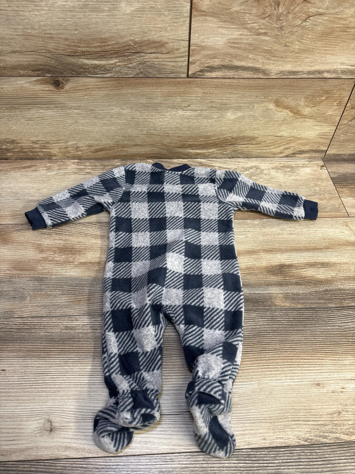 Front view of PL Baby plaid blanket sleeper showcasing grey plaid pattern and footed design on a wood surface