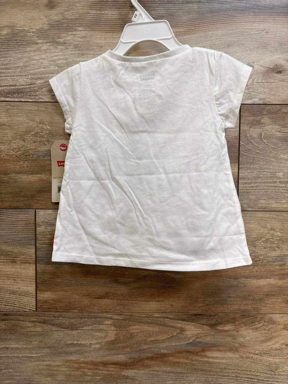 Back view of white Levi's toddler short-sleeve t-shirt showing crew neck and side Levi's tag on wood floor background