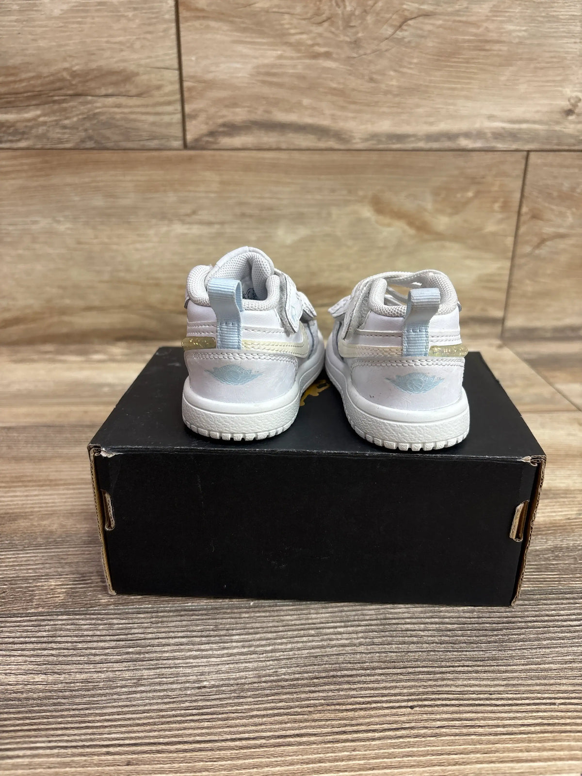 Rear view of Air Jordan 4 Retro TD Hyper Violet sneakers with heel tabs and Jordan logos on a black shoebox