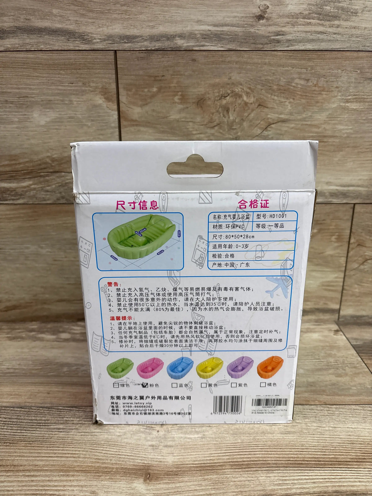 Back of green Letoy inflatable bathtub packaging showing 80 by 50 by 28 cm dimensions and ages 0 to 3 years on wood flooring