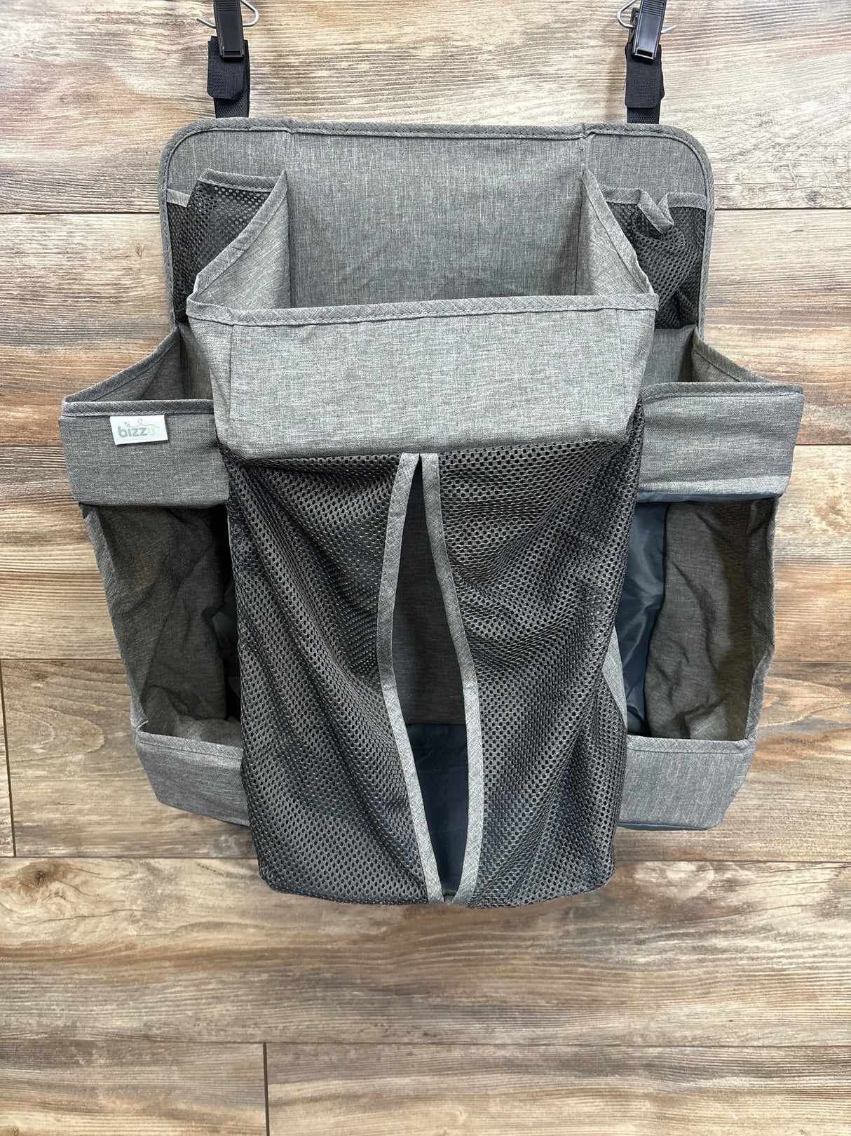 Gray hanging diaper caddy organizer with mesh pockets on wood background