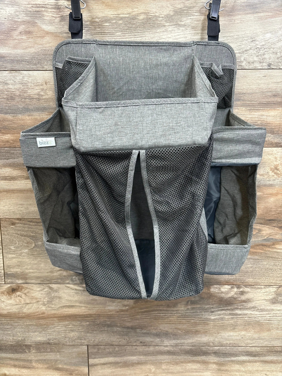 Gray hanging diaper caddy organizer with mesh pockets on wood background