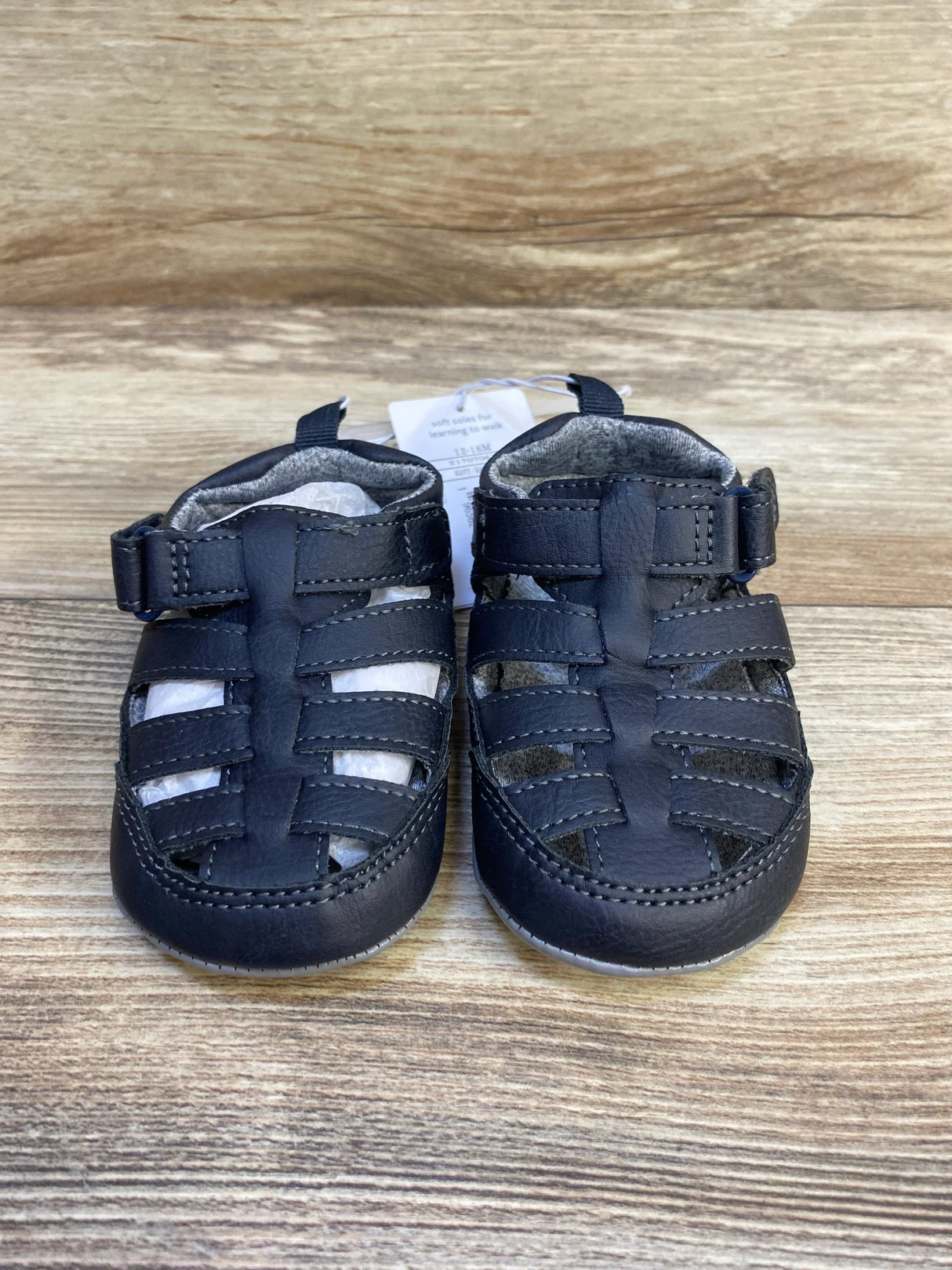 Black toddler leather sandals with closed toe on wooden background