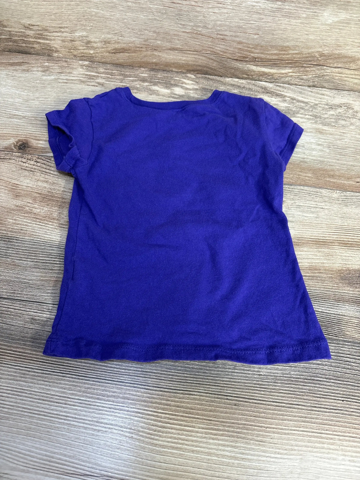 Back flat lay of Children's Place purple short-sleeve toddler shirt size 4T showcasing crew neck and slight sleeve ruffle on wood background