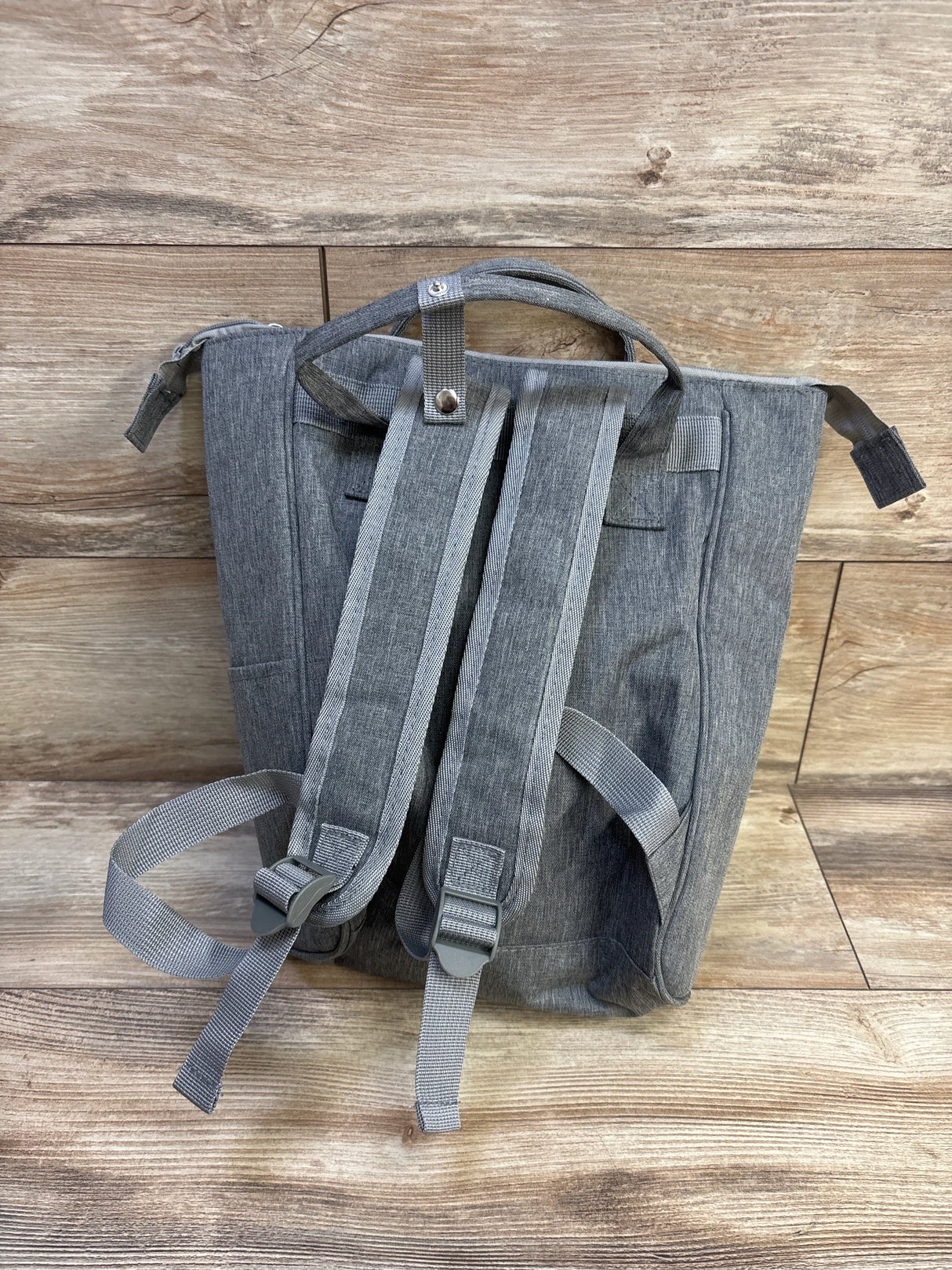 Back view of Enfamil Wonderbag insulated diaper backpack showcasing padded adjustable shoulder straps, top handle, and grey heather fabric on wood background