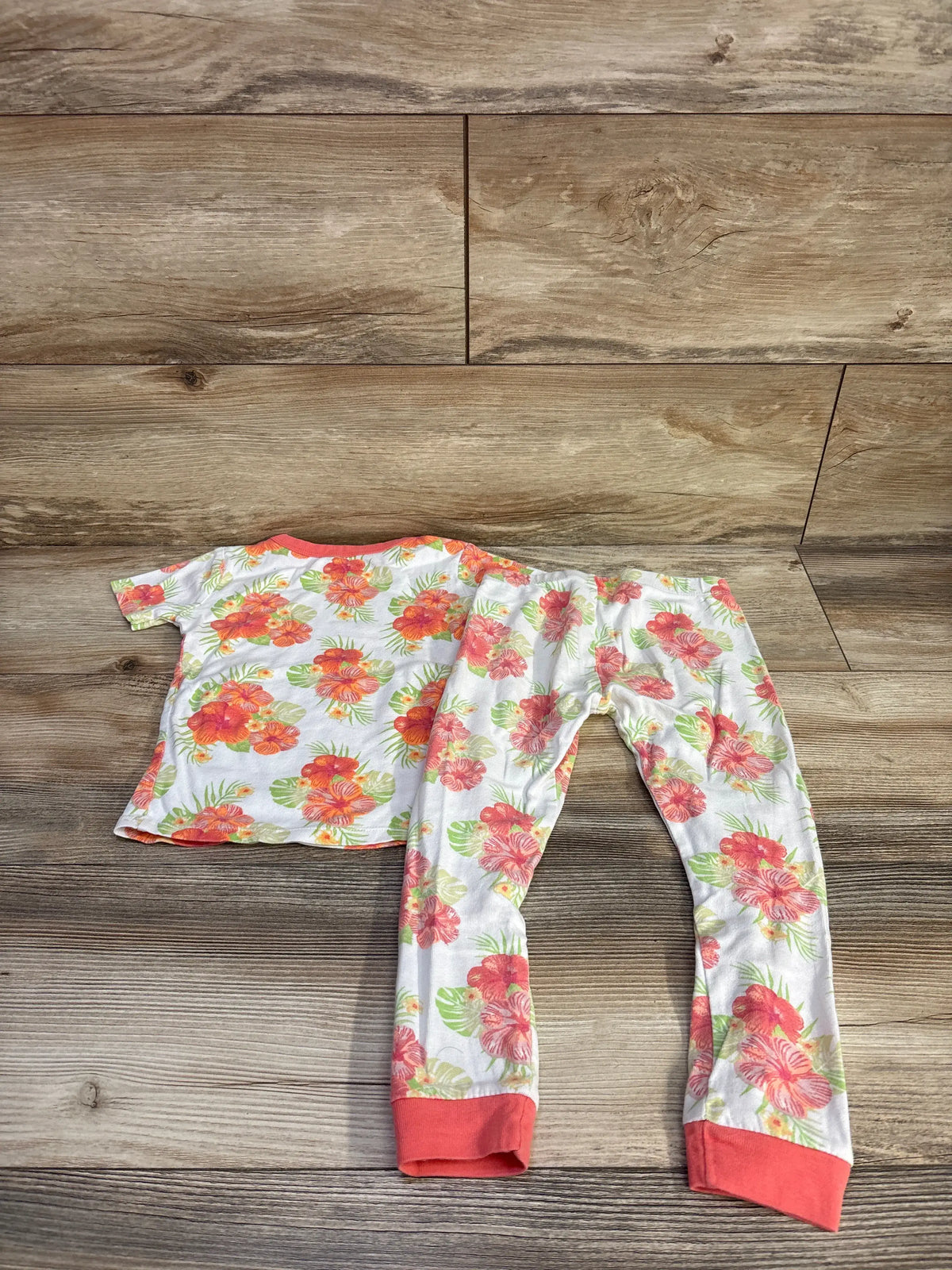 Overhead view of Member’s Mark 2pc Pajama Set White sz 4T showcasing colorful floral print and coral trim on a wood-look floor
