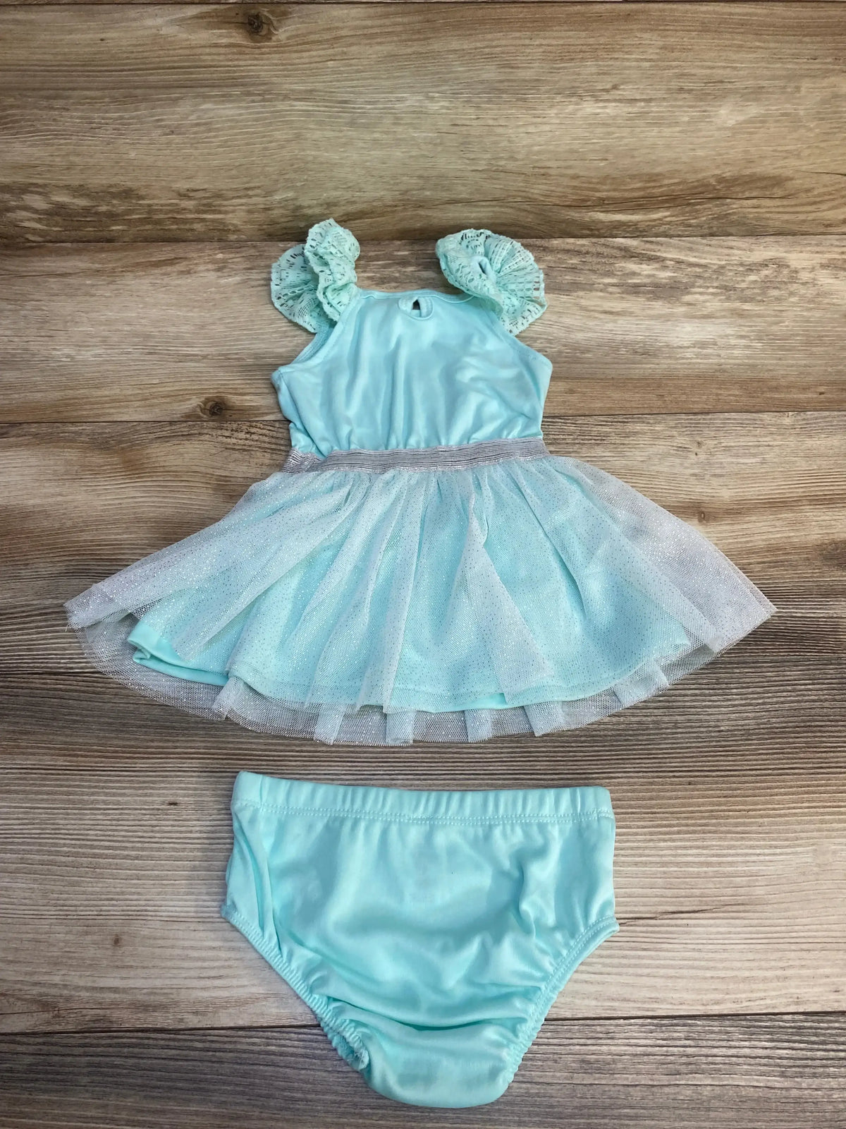 Light blue baby dress with ruffle sleeves and matching diaper cover on wooden background