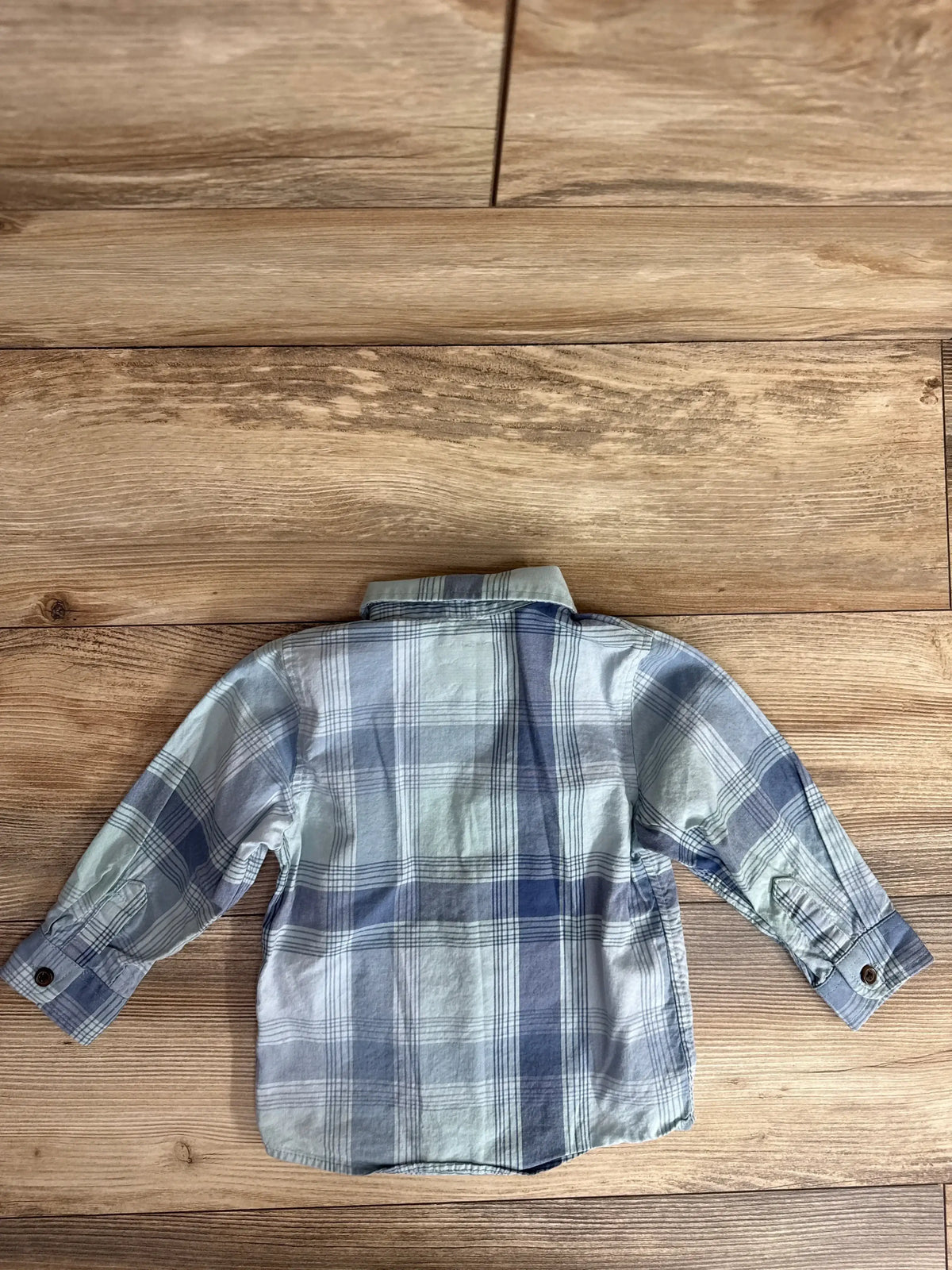 Back of Cat and Jack toddler plaid button-up shirt showing blue and gray checks and button cuffs on wood background