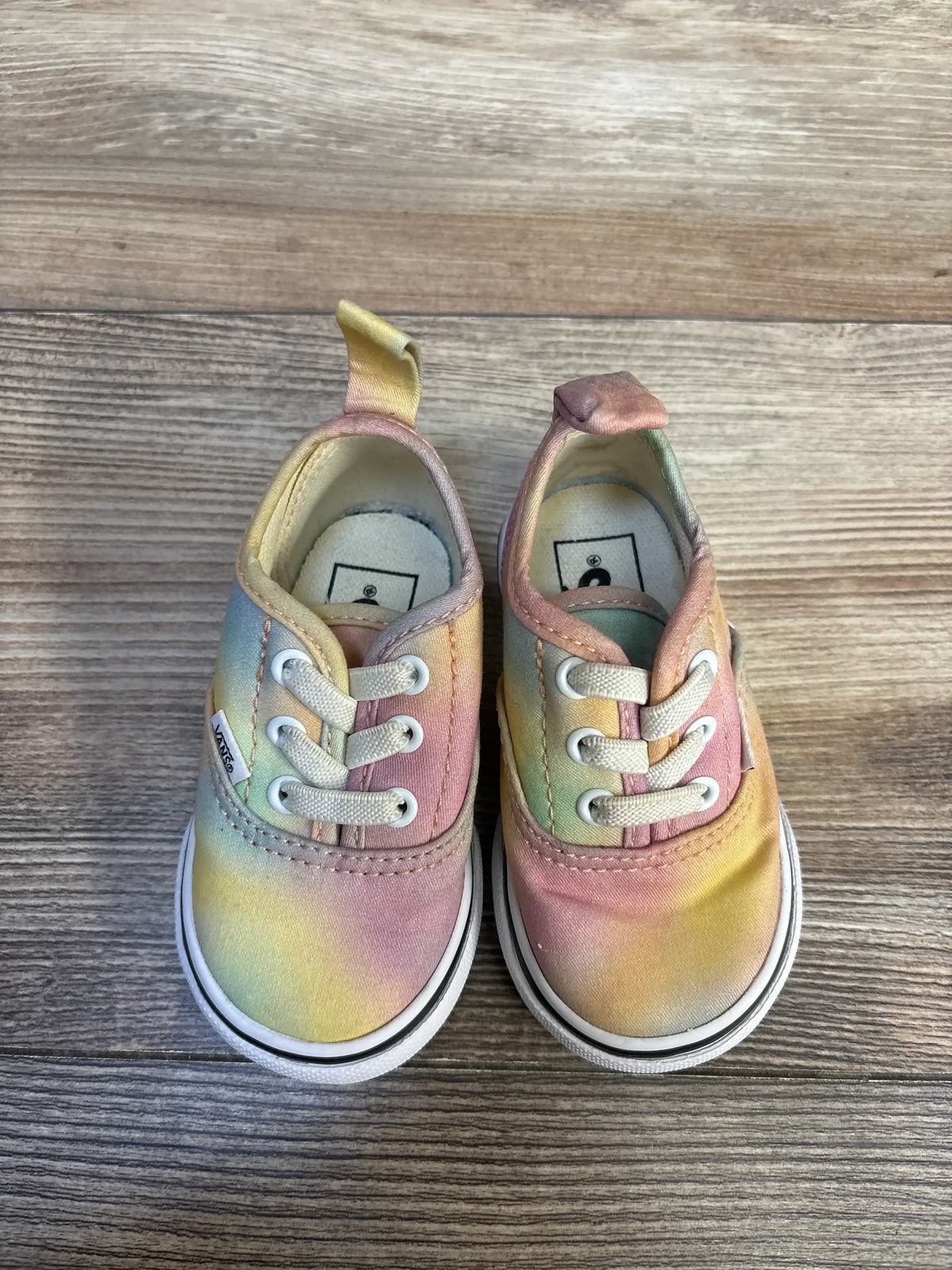 Angled top view of Vans Authentic Elastic Aura Shift toddler sneakers showing pastel tie-dye canvas and elastic laces on wood background