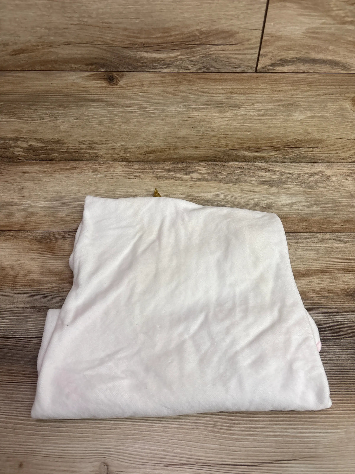 Folded cream-colored Cloud Island unicorn hooded infant towel on a wooden surface