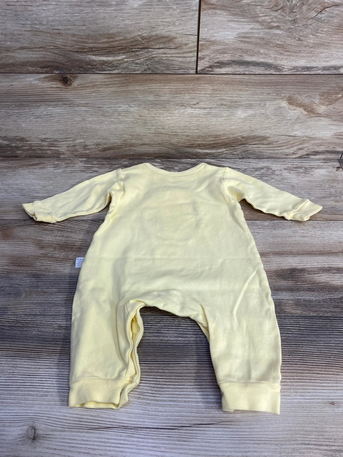 Back flat-lay of yellow bunny coverall showcasing long sleeves and cuffed leg openings with wood plank background