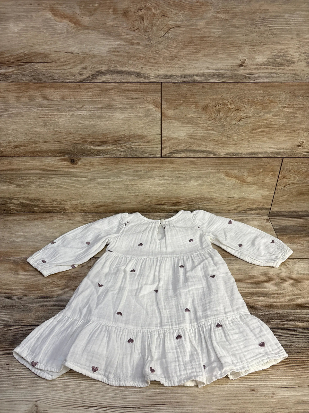 Front view of a white Cat & Jack toddler dress showcasing embroidered hearts and tiered gauze skirt on a wood floor