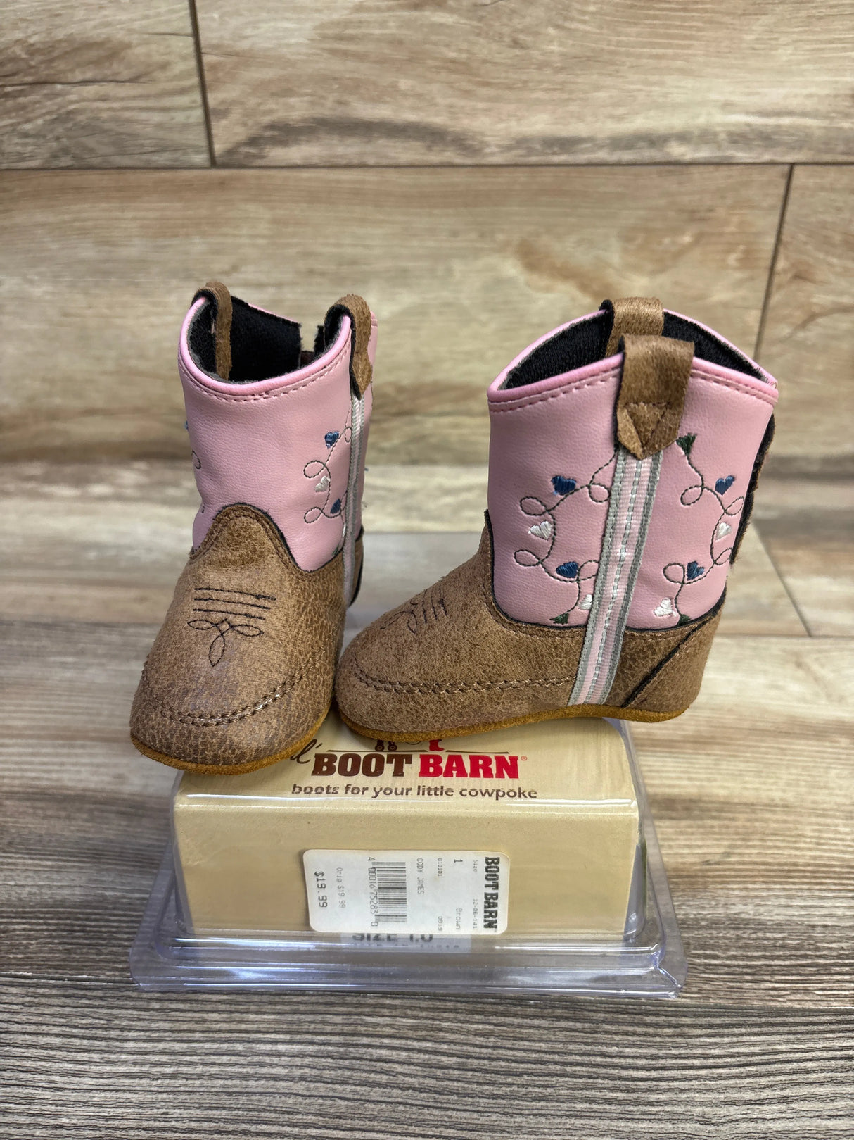 Angled view of Old West Poppets toddler boots showing pink embroidered shaft and brown faux suede toe on wood background