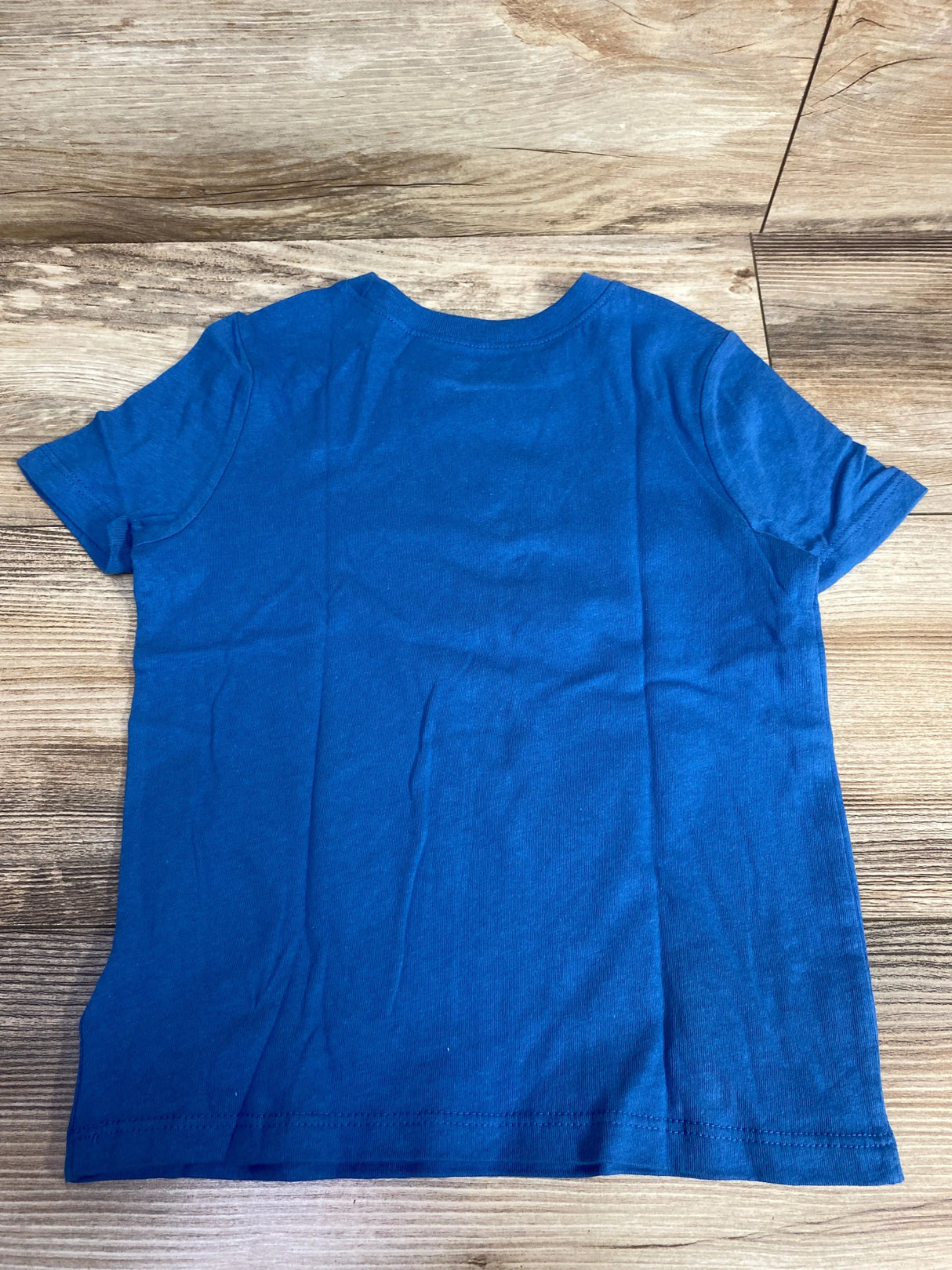 Plain blue short sleeve t-shirt on wood background, basic kids clothing