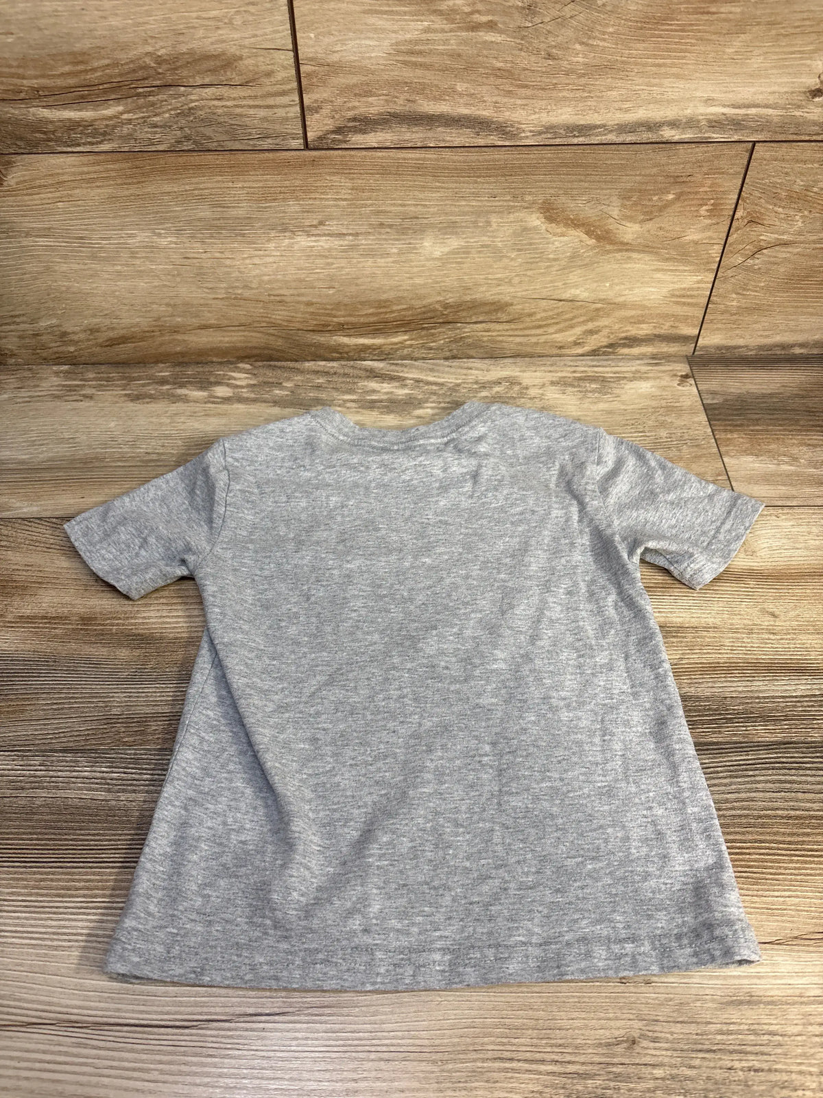 Front view of Tommy Hilfiger grey shirt in size 3T showcasing short sleeves and relaxed fit on a wood-look floor