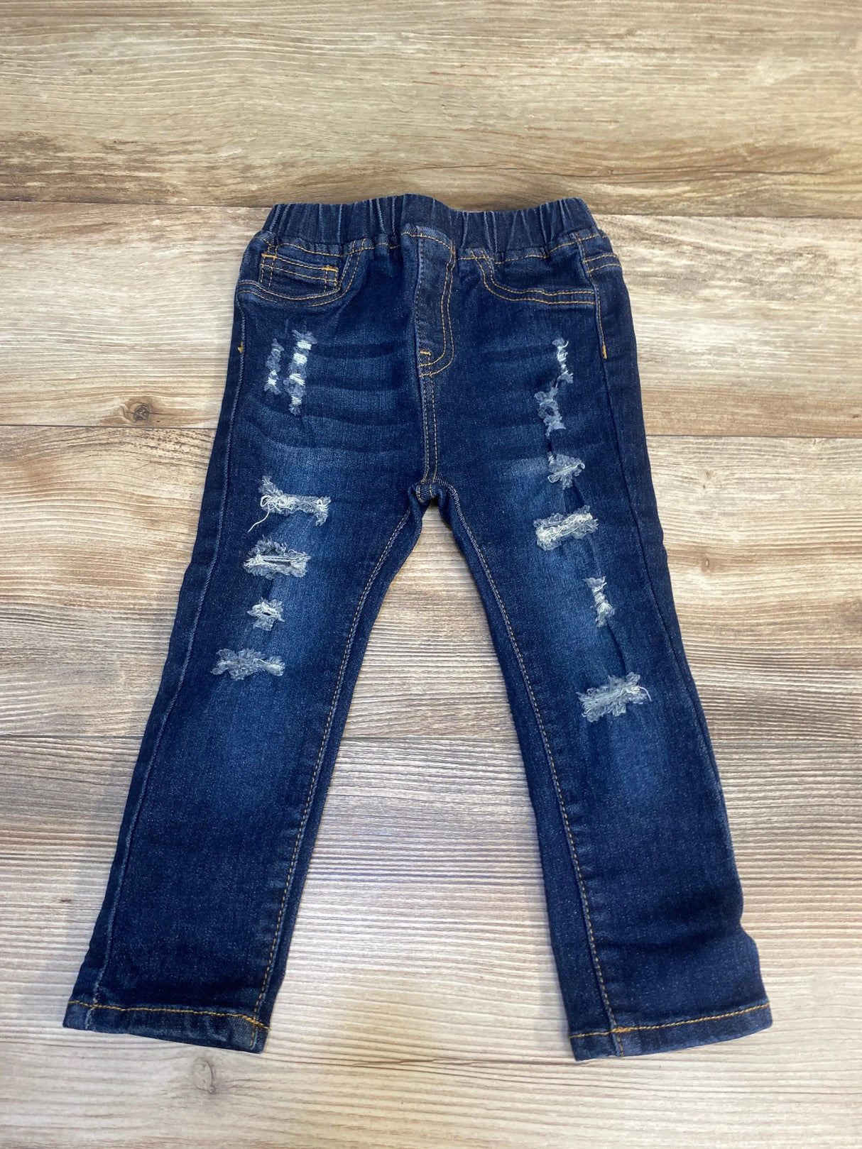 Distressed dark wash kids jeans with elastic waistband on wood background