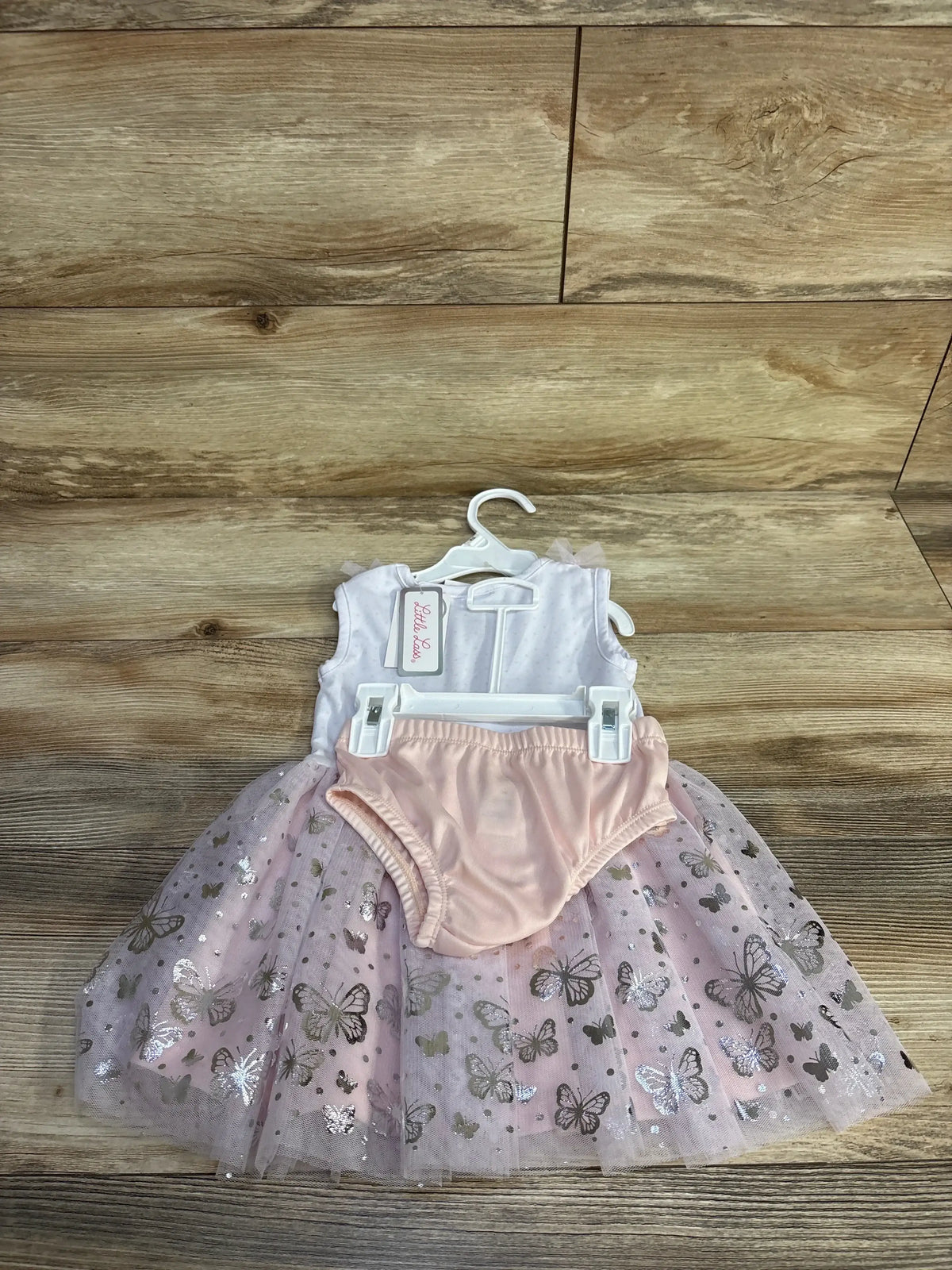 Front view of lilac baby dress and bloomers showing metallic butterfly tulle skirt and sleeveless bodice on wood floor