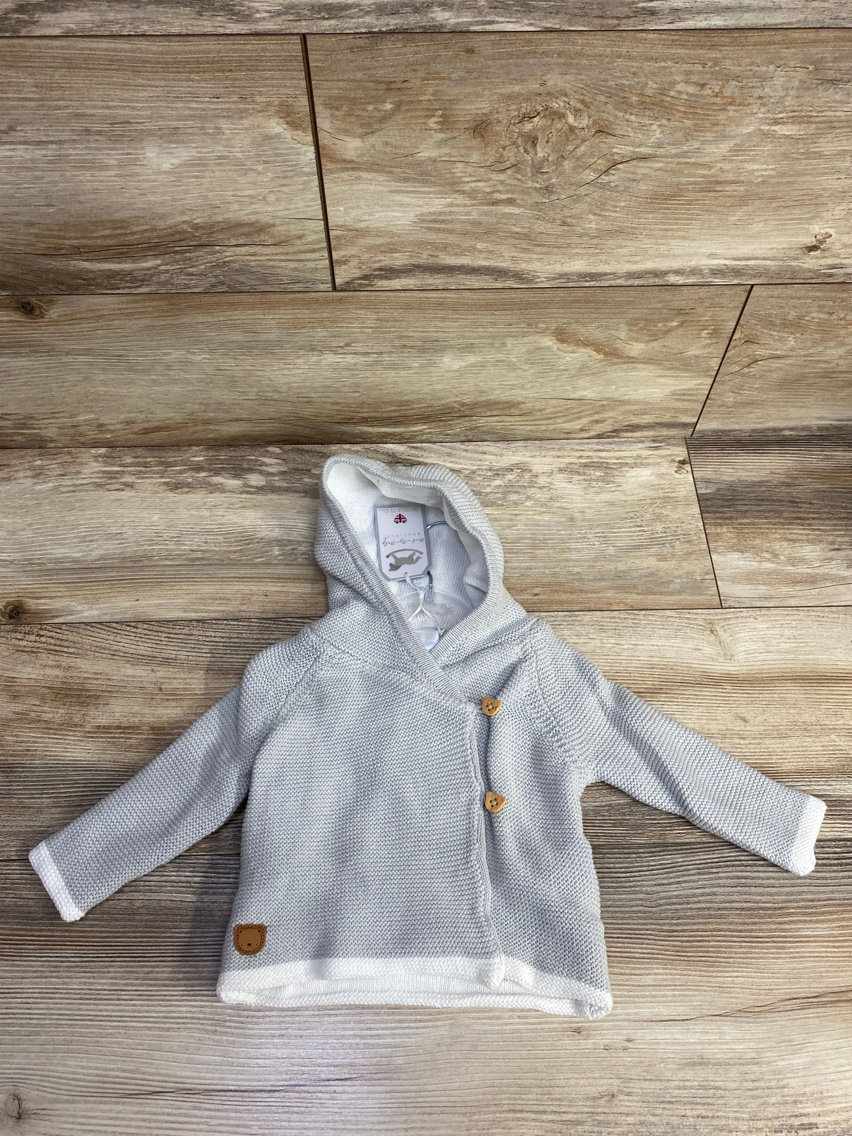 Light gray baby hooded cardigan with wooden buttons on wood plank background