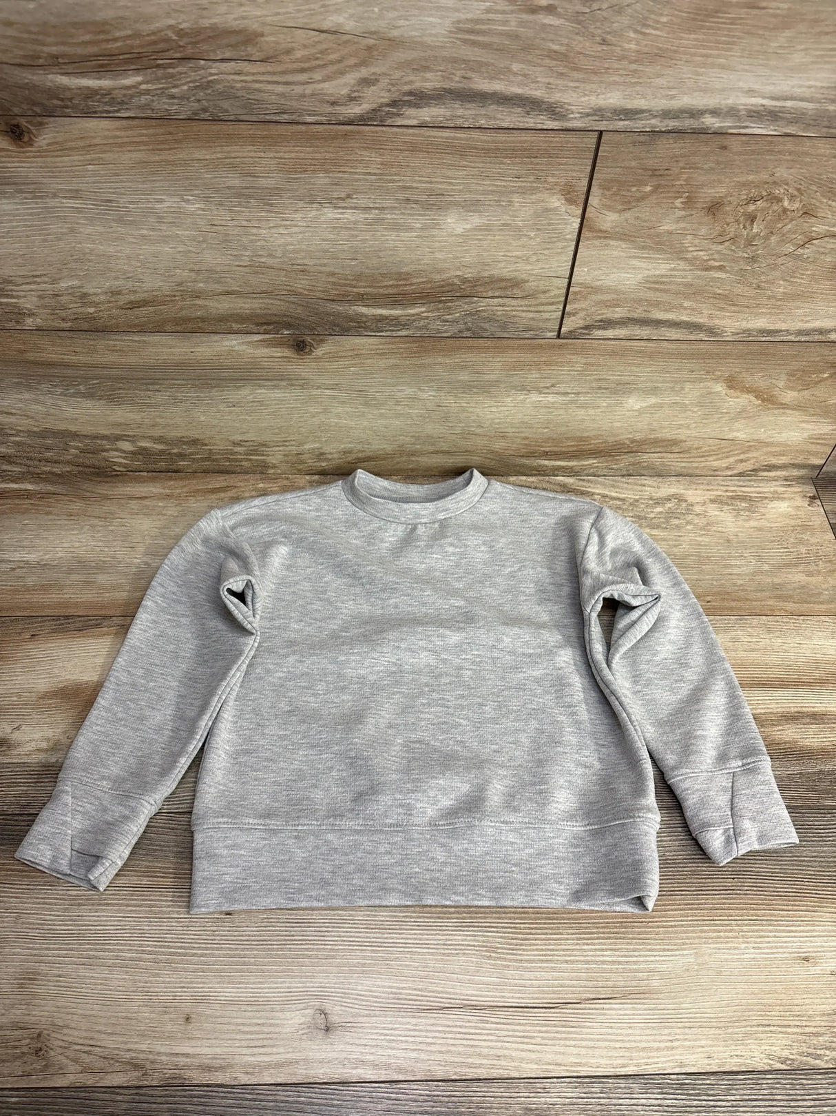 Light gray long sleeve kids sweatshirt displayed on wood background