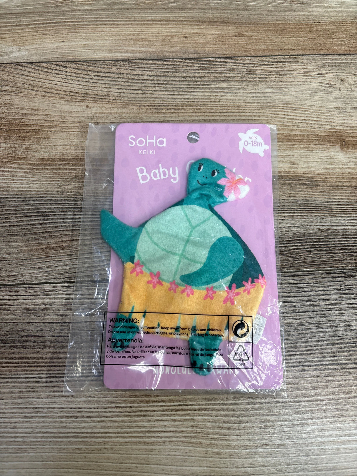 SoHa Keiki baby rattle toy shaped like a smiling green sea turtle with pink flowers on a purple backing card, suitable for ages 0-18 months