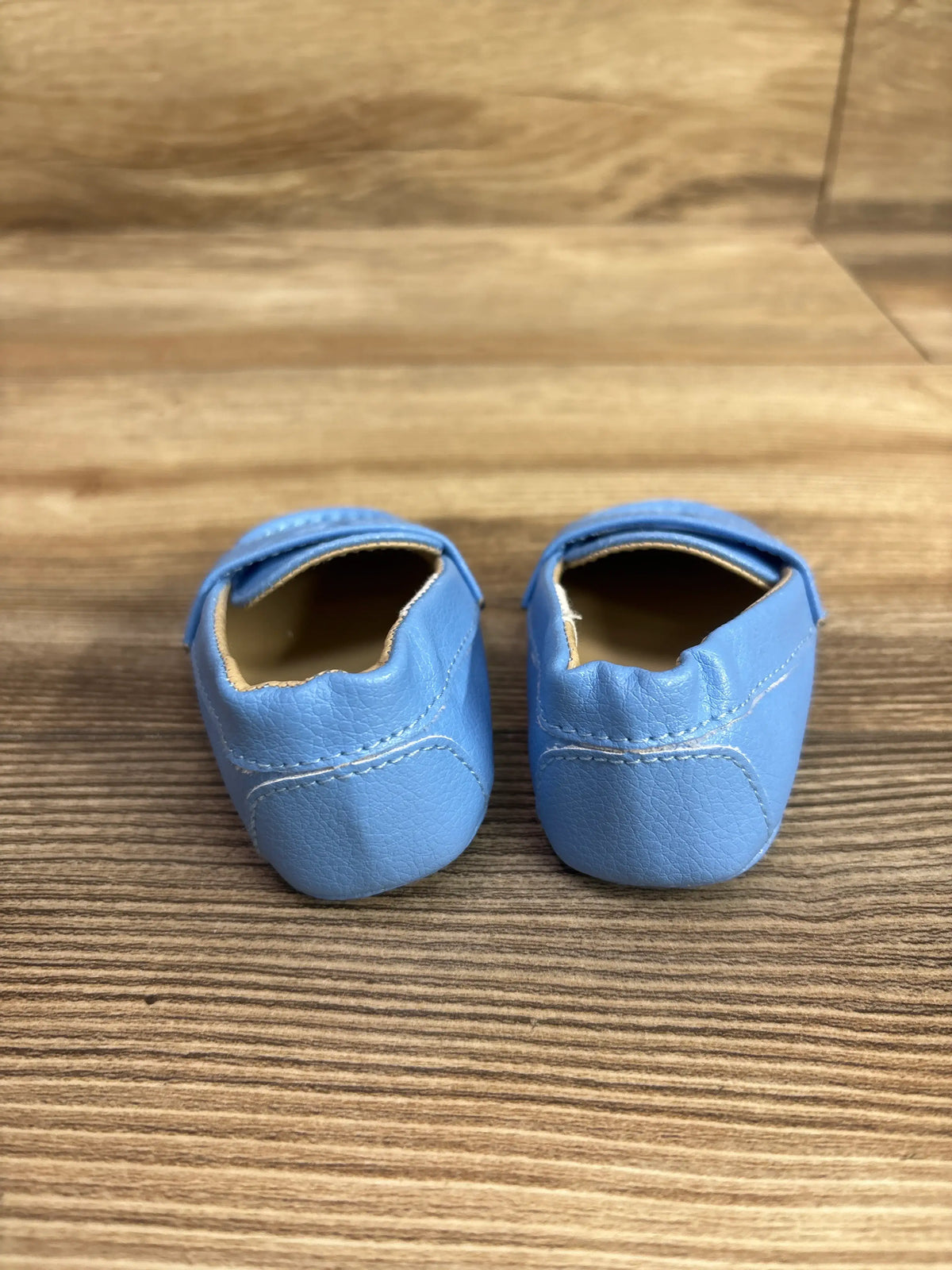 Pair of light blue Janie & Jack Penny loafer shoes for babies on a wooden surface.